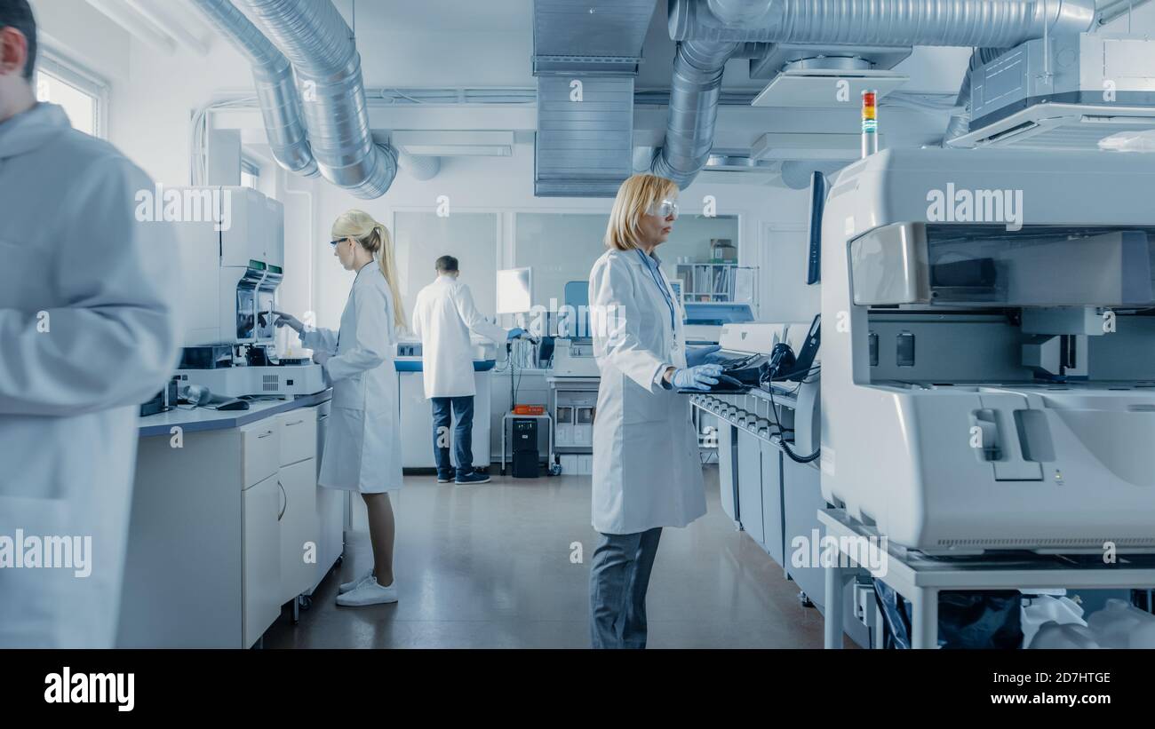 Équipe de chercheurs scientifiques travaillant sur l'ordinateur, avec l'équipement médical, l'analyse d'échantillons de sang et de matériel génétique avec des machines spéciales dans le Banque D'Images
