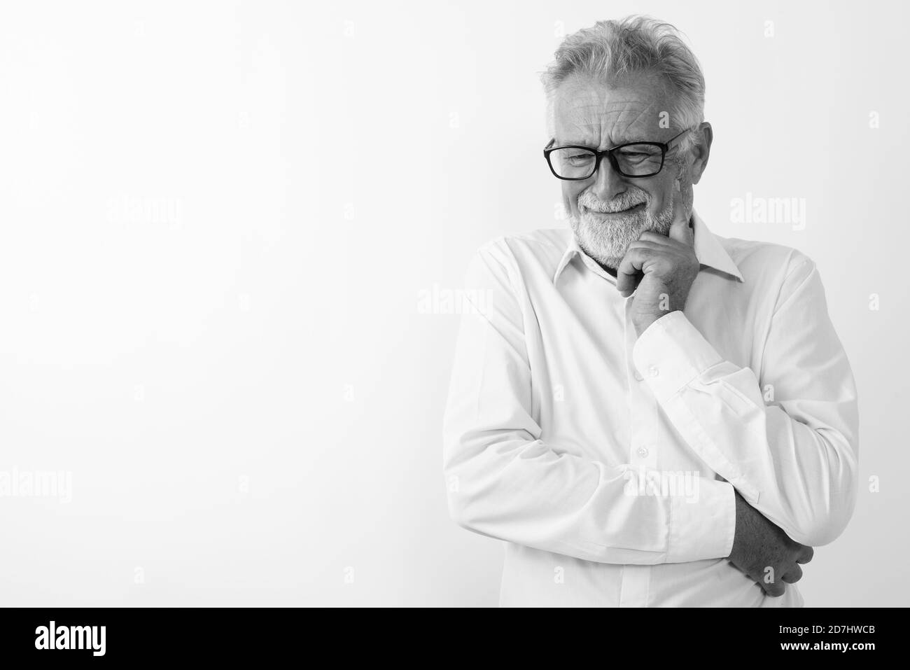 Studio shot of senior triste pensée homme barbu avec des lunettes en pleurant contre fond blanc Banque D'Images