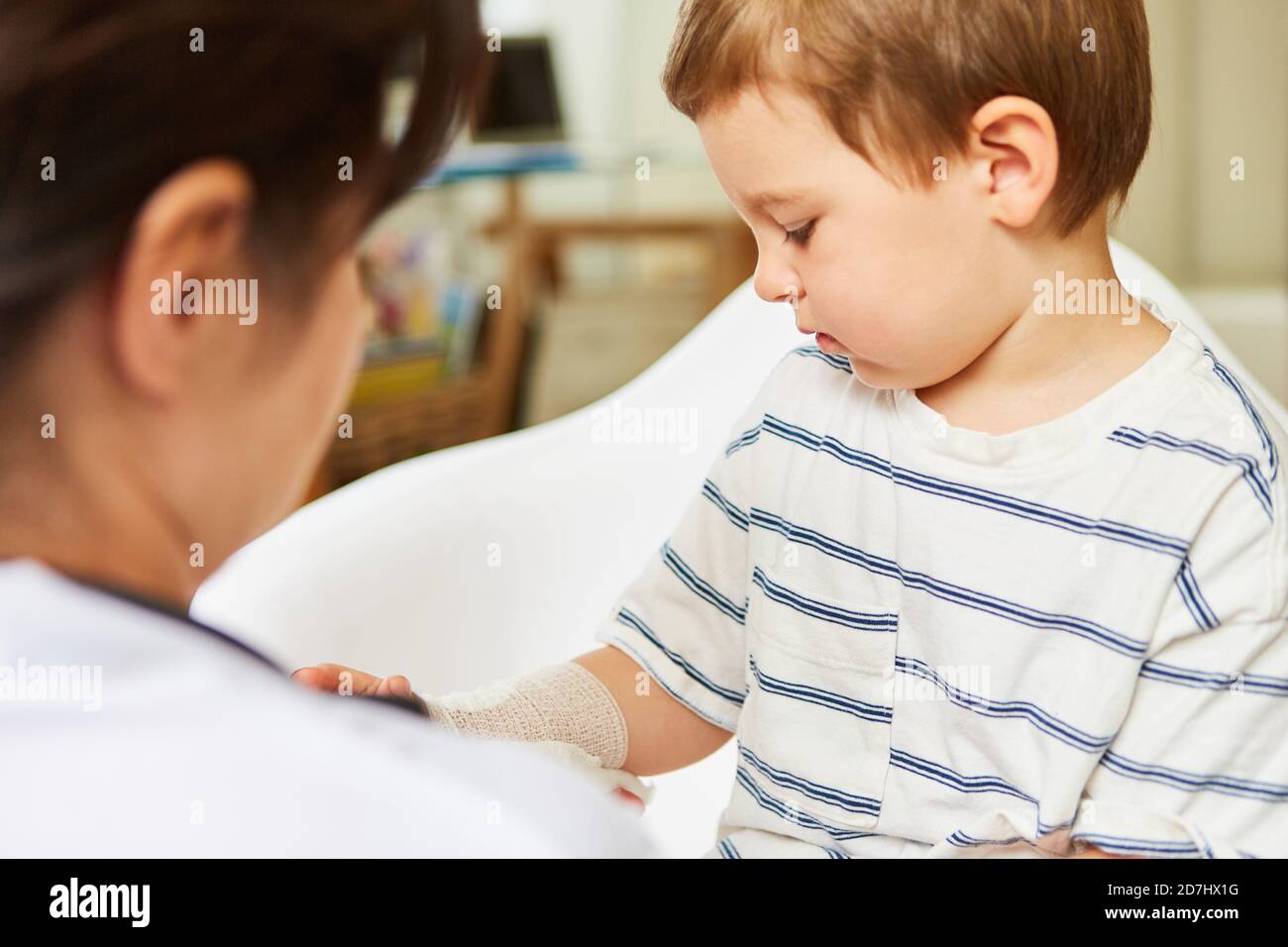 Le pédiatre lie le bandage autour du bras ou du poignet de l'enfant dans cas d'entorse Banque D'Images