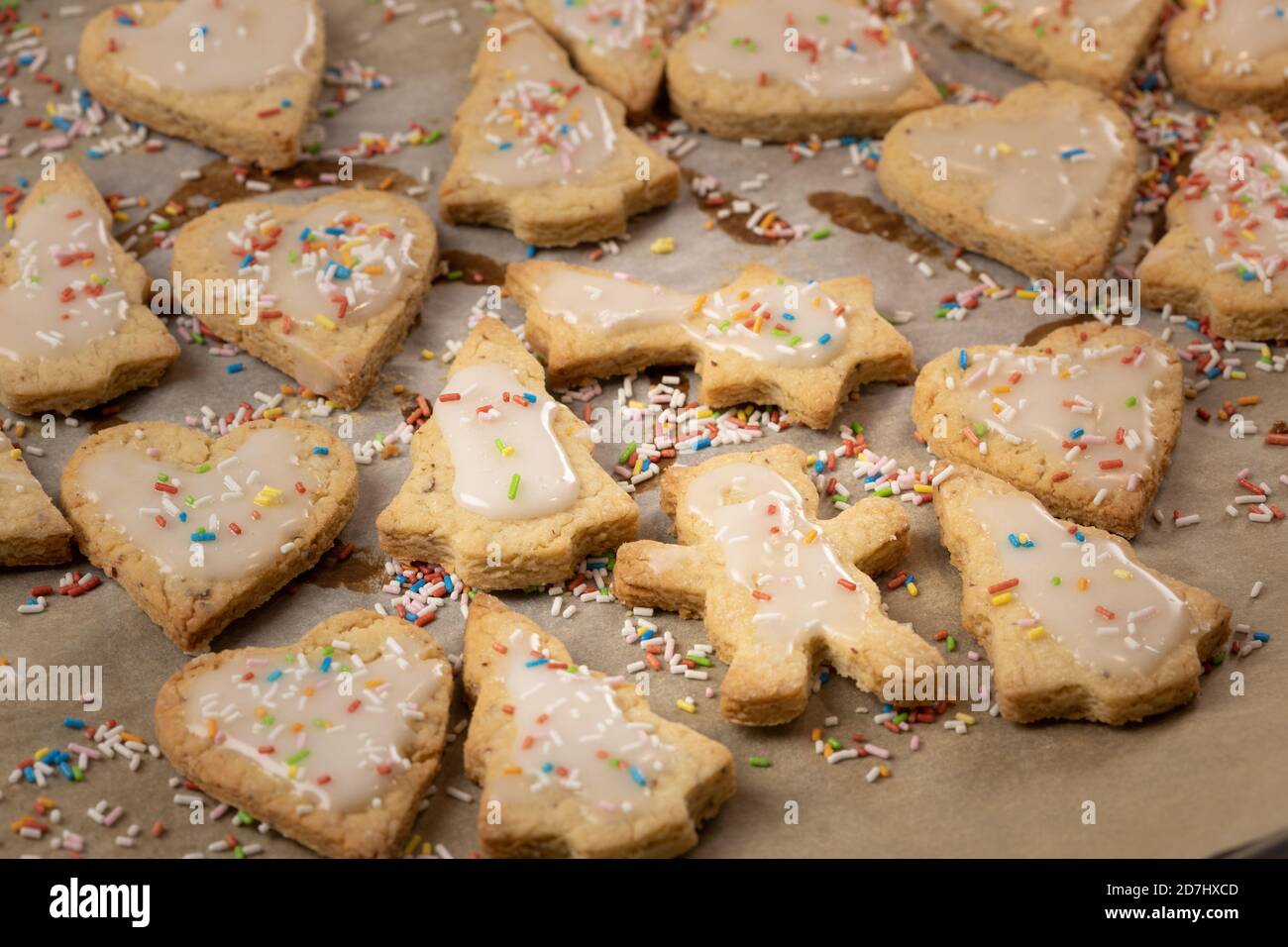 Cuisson de Noël : biscuits à croûte courte avec glaçage au sucre sur du papier de cuisson Banque D'Images