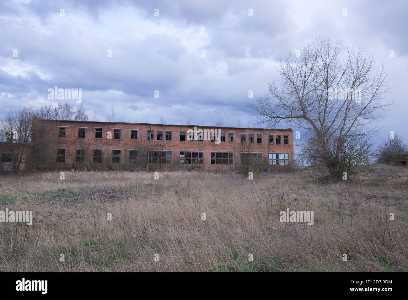 Un bâtiment abandonné en briques de deux étages. Paysage de soirée nuageux. Ciel nuageux. Banque D'Images