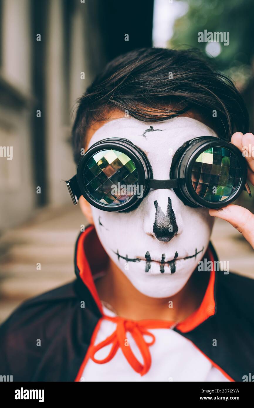 Garçon portant un costume d'Halloween avec peinture pour le visage et lunettes de protection Banque D'Images