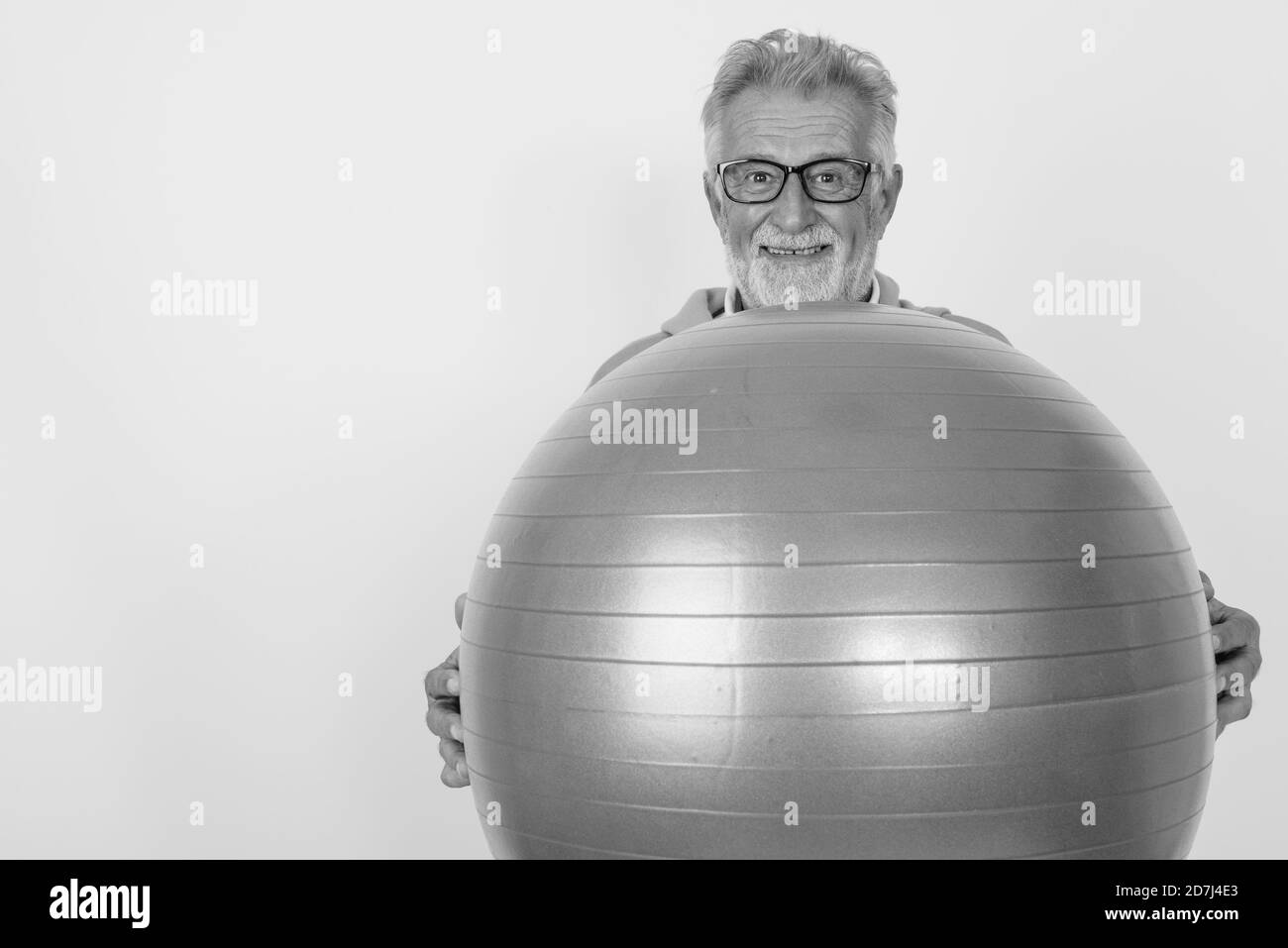 Studio shot of happy senior man smiling barbu en maintenant le ballon de gymnastique gym prêt à contre fond blanc Banque D'Images