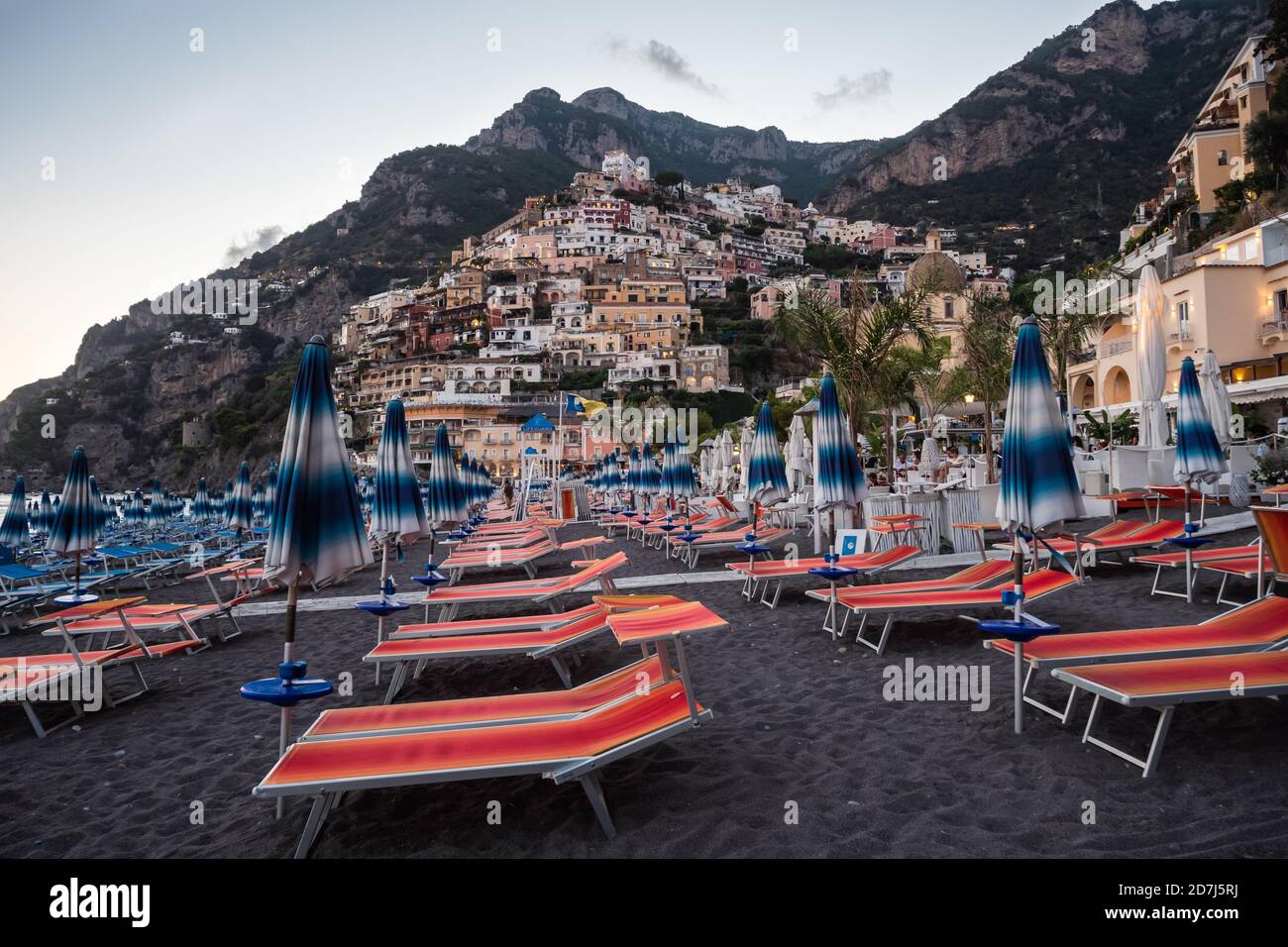 Positano, Italie - 24 2020 août : plage Positano Spiaggia avec chaises de plage et parasols Orange le soir avec vue sur le village Banque D'Images