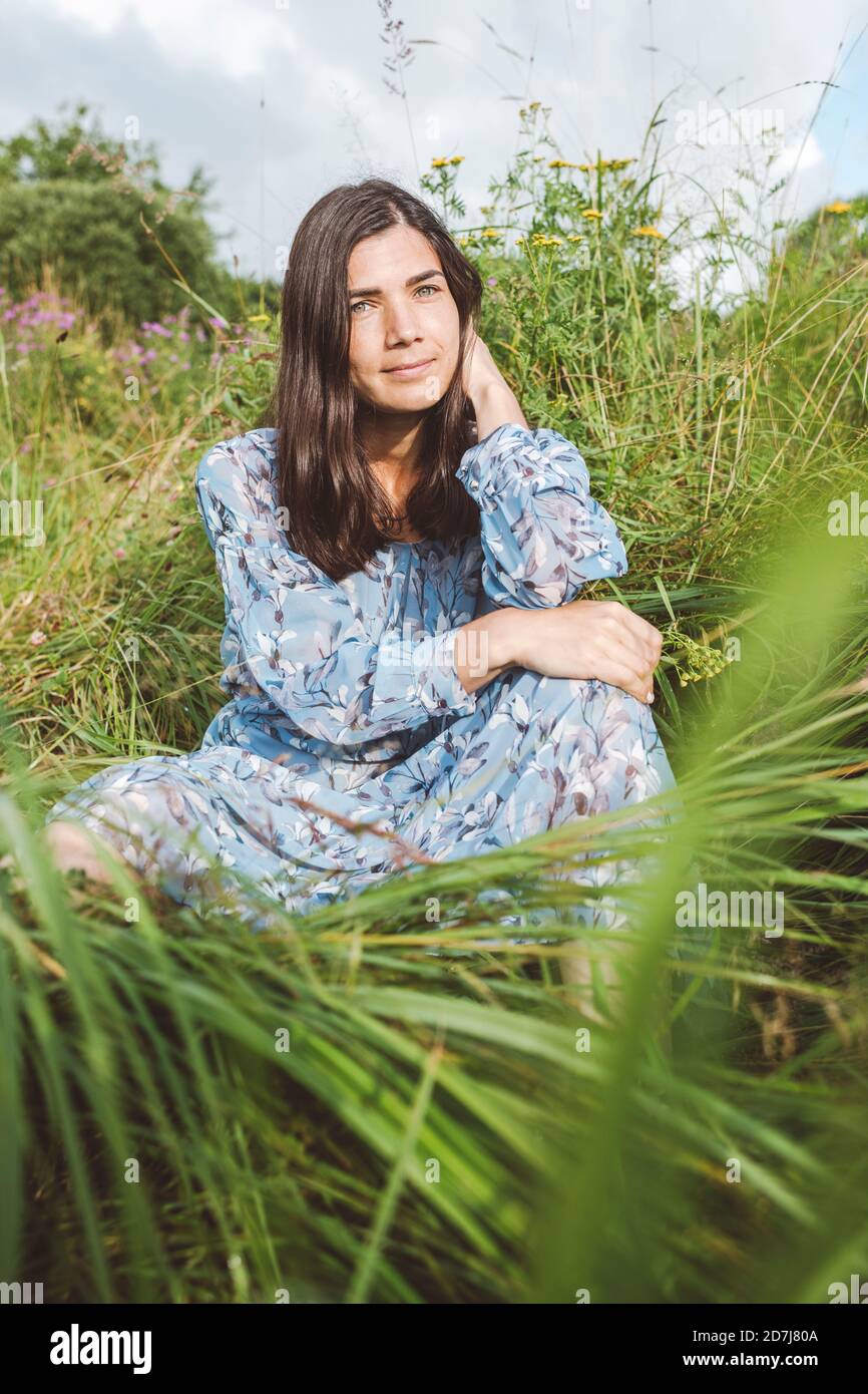 Femme adulte de taille moyenne assise parmi les plantes sur terre Banque D'Images