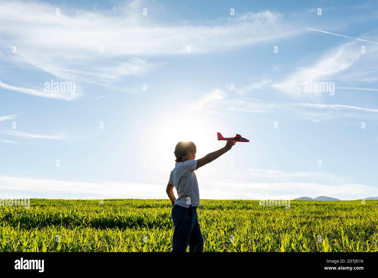 Un garçon insouciant jouant avec un jouet d'avion contre un ciel dégagé Banque D'Images