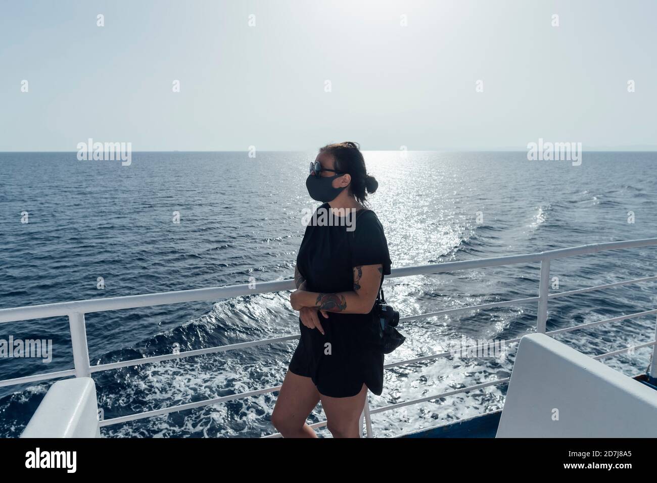 Femme portant un masque de visage debout près de la main courante d'une embarcation de passager Banque D'Images