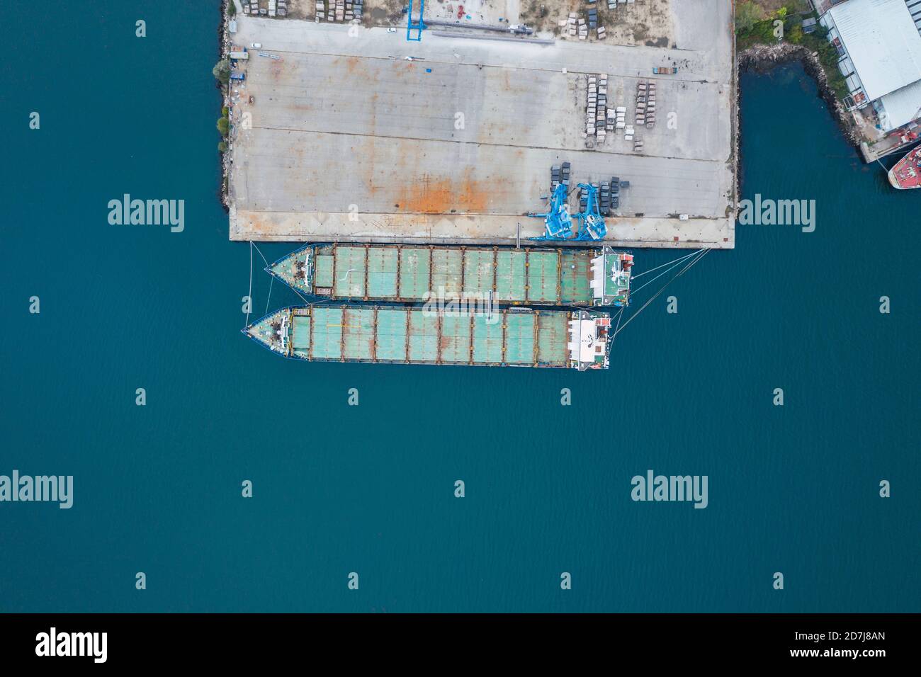 Vue de drone des navires-conteneurs amarrés par quai au port sur la mer bleue Banque D'Images