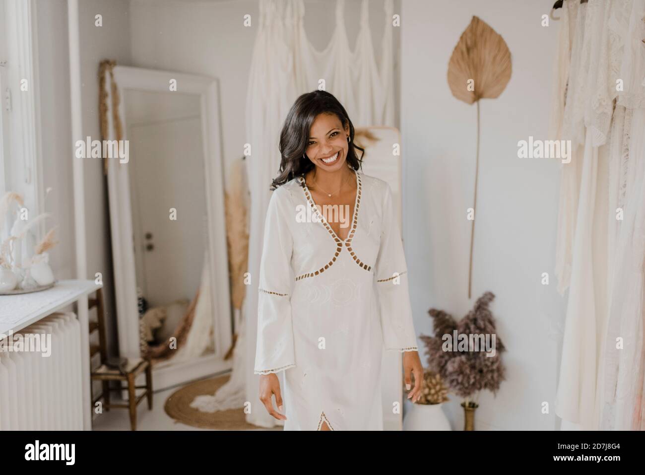 Jeune mariée souriante debout à la boutique de robes de mariage Banque D'Images