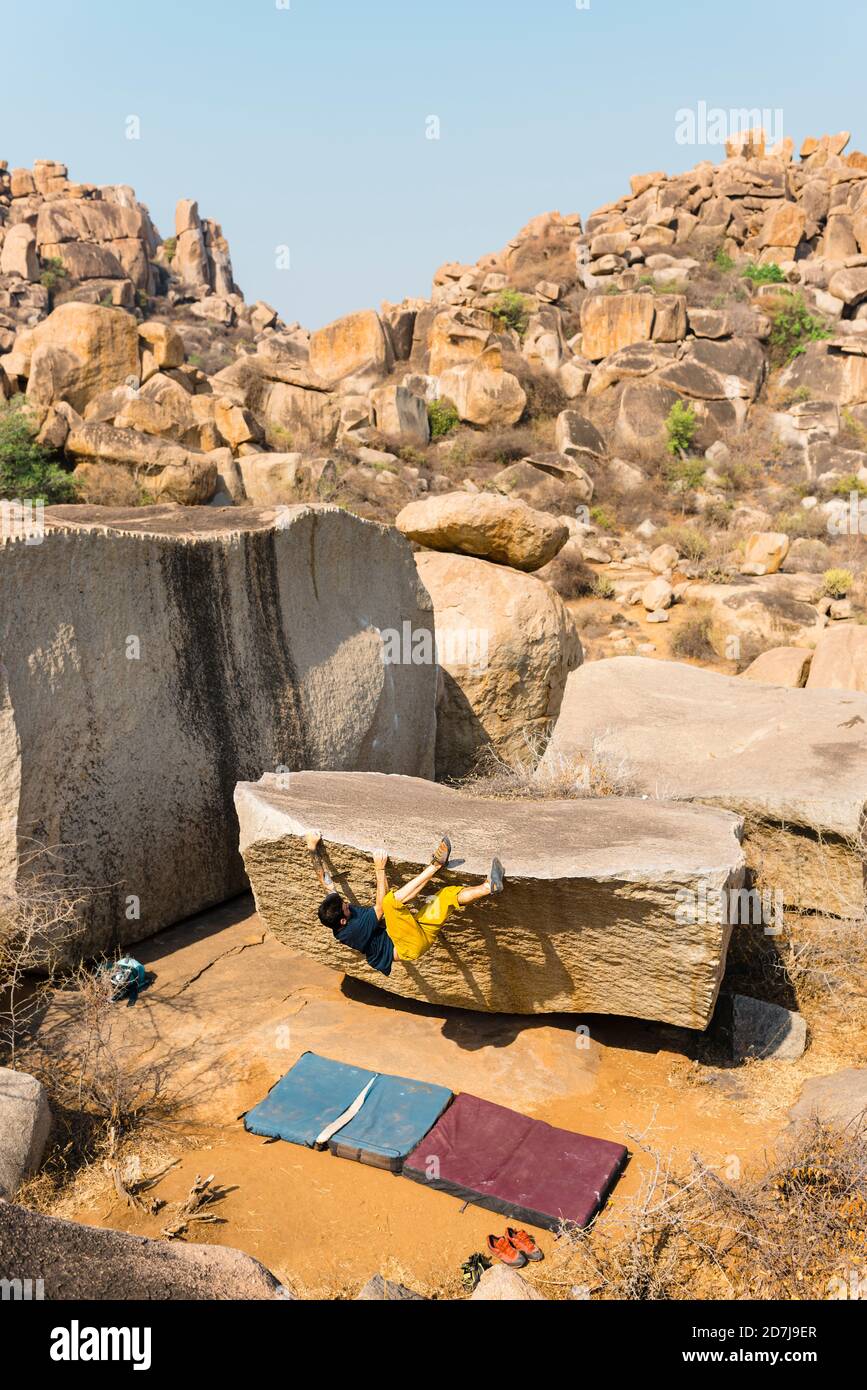 Grimpeur de roche se trouvant au-dessus d'un rocher couché à pied de colline rocheuse Banque D'Images