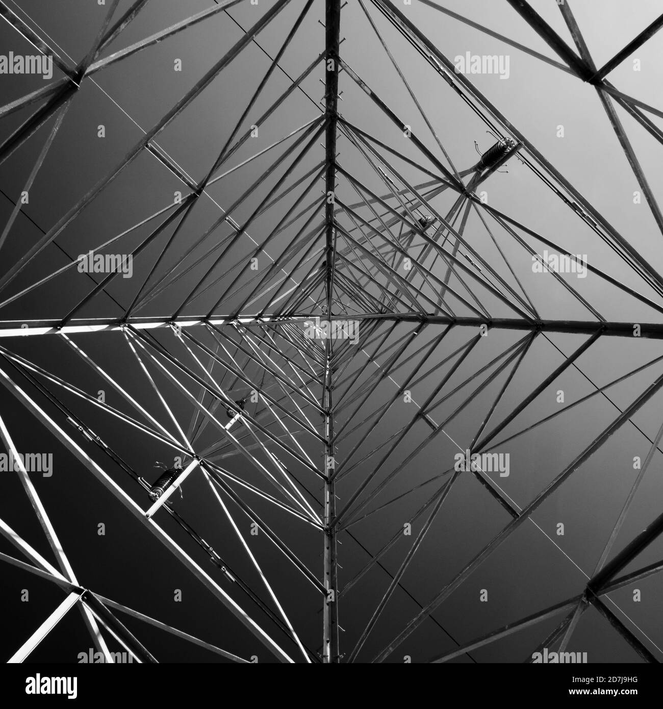 Une vue abstraite en noir et blanc qui regarde vers le haut un pylône d'électricité haute tension. Banque D'Images