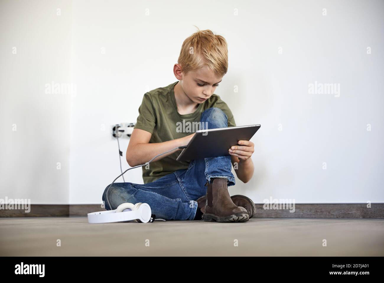 Petit garçon jouant sur une tablette numérique tout en étant assis dans un nouveau maison Banque D'Images