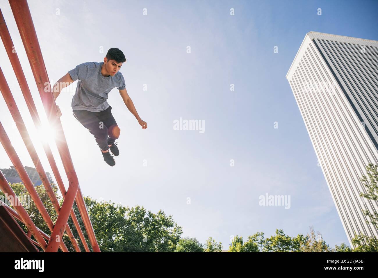 Jeune homme sautant sur la rampe en train de faire un parking dans un ciel dégagé en ville Banque D'Images