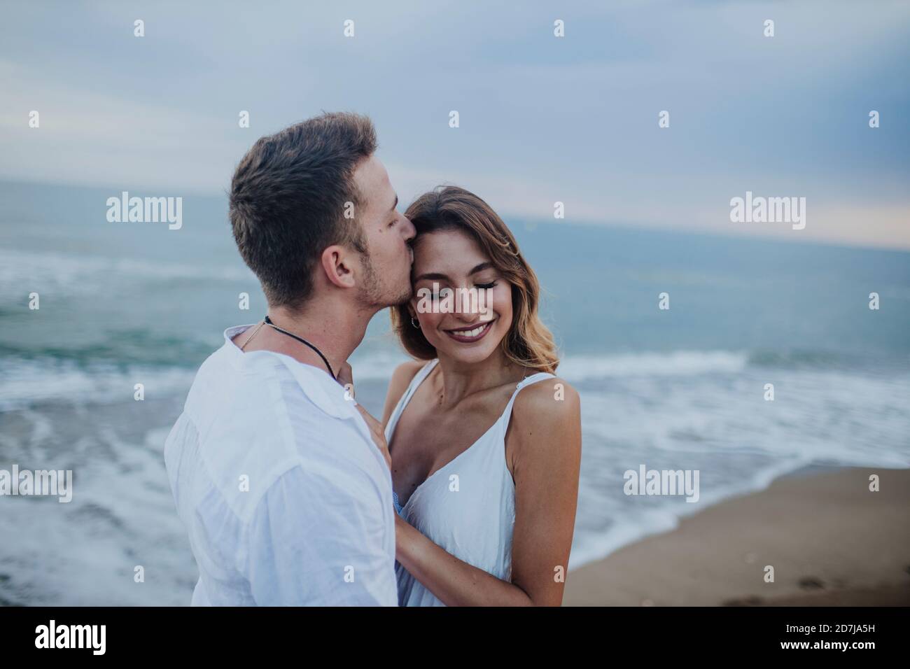 Homme embrassant la femme en se tenant à la plage Banque D'Images