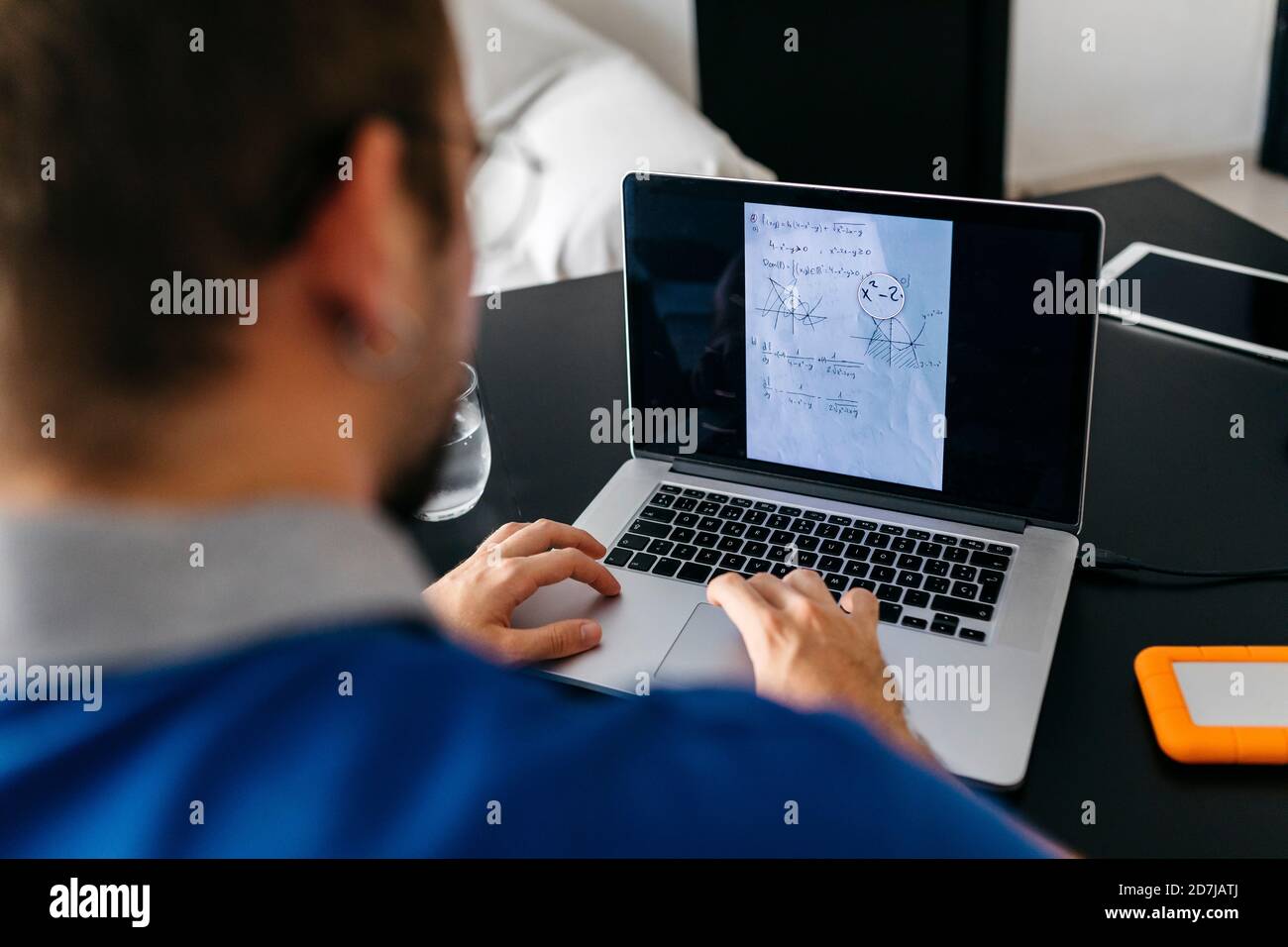 Un étudiant de sexe masculin fait ses devoirs de mathématiques sur un ordinateur portable à la maison Banque D'Images