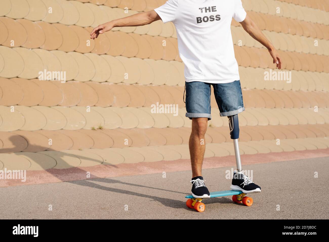 Jeune homme avec un membre et un pied artificiels debout sur une planche à roulettes sur le terrain de sport Banque D'Images
