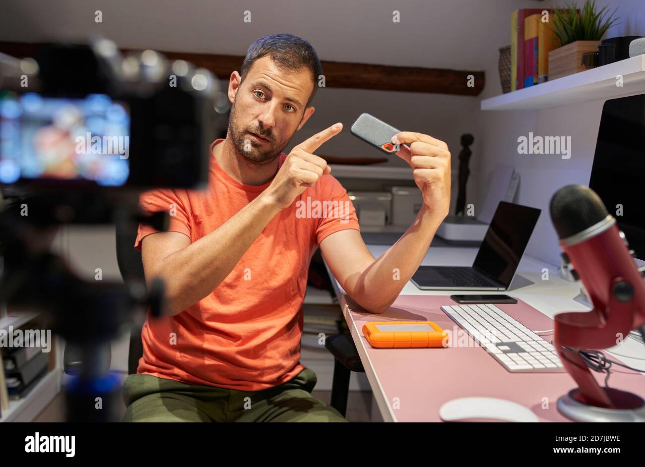 Homme de taille moyenne adulte pointant vers un disque dur externe pendant  la vidéo enregistrement sur caméra à la maison Photo Stock - Alamy