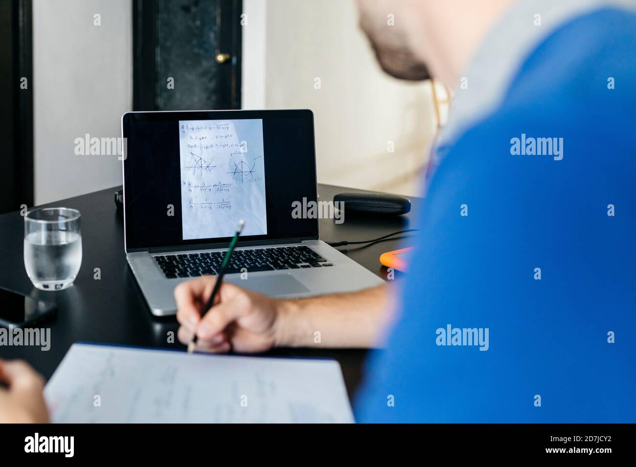 Un étudiant d'université fait ses devoirs de mathématiques sur un ordinateur portable à la maison Banque D'Images