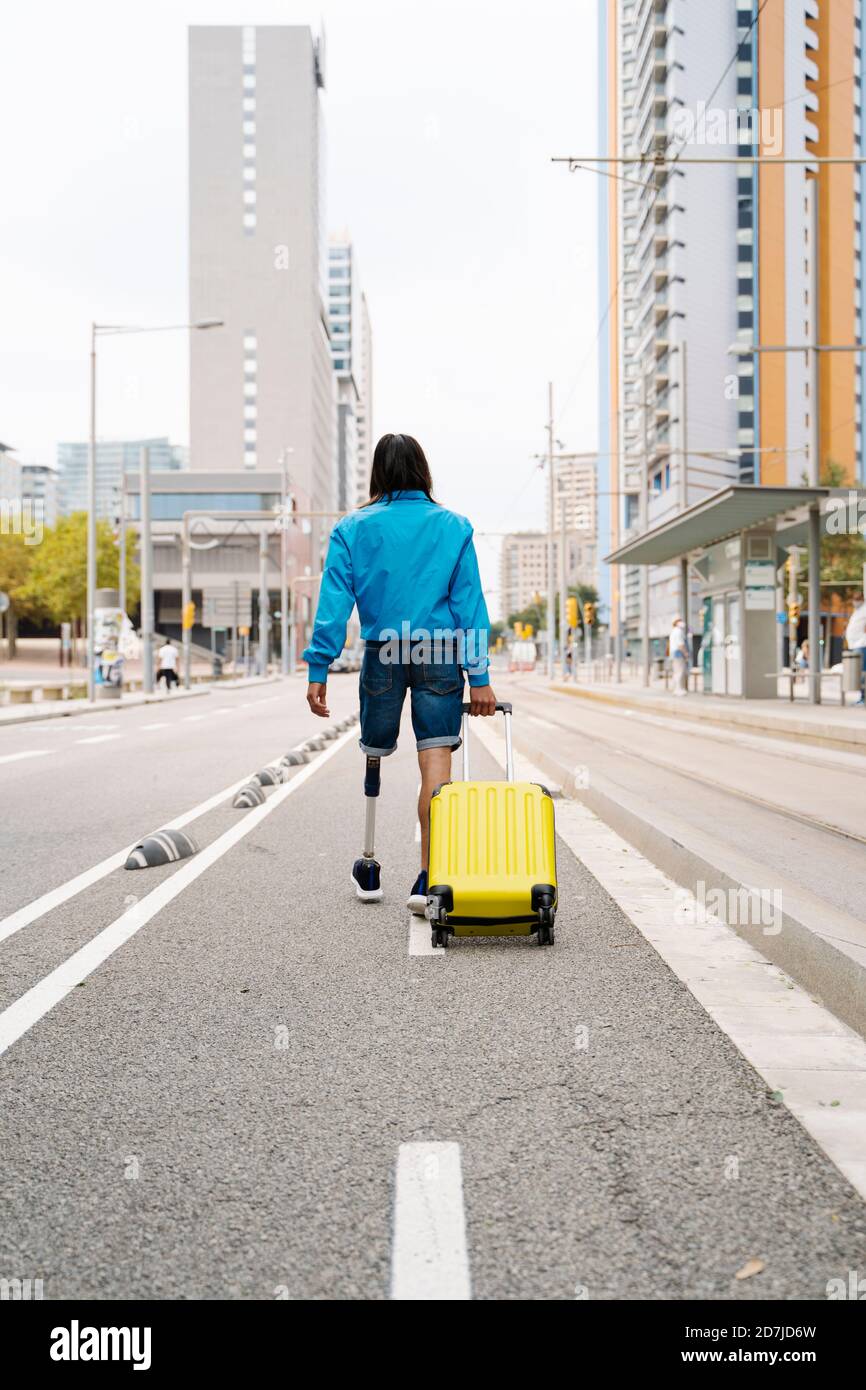 Jeune homme marchant avec des bagages sur la route en ville Banque D'Images