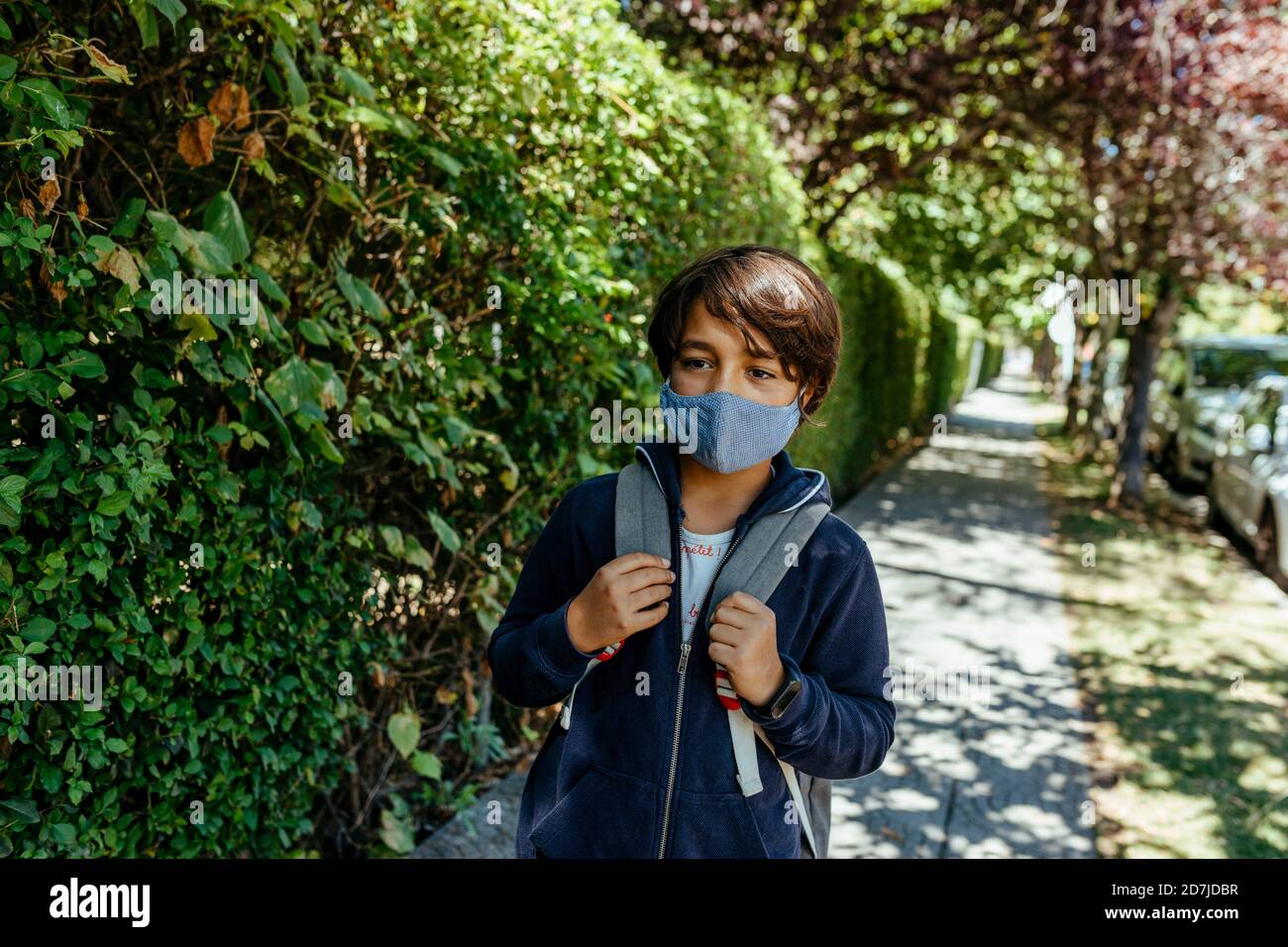 Garçon portant un masque qui regarde loin en se tenant debout près des plantes chemin de pied Banque D'Images
