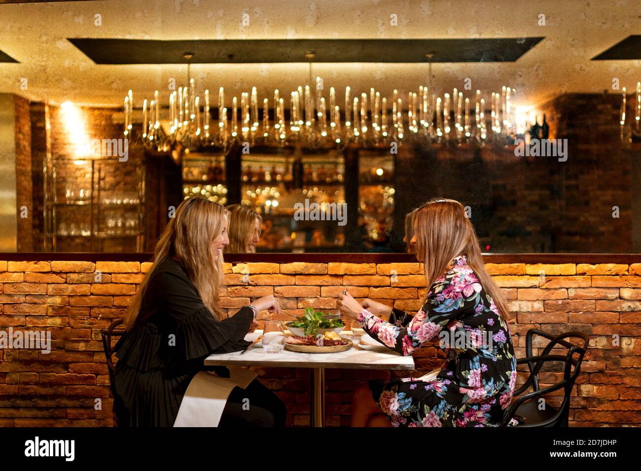 Des amis qui parlent tout en mangeant de la nourriture au restaurant Banque D'Images