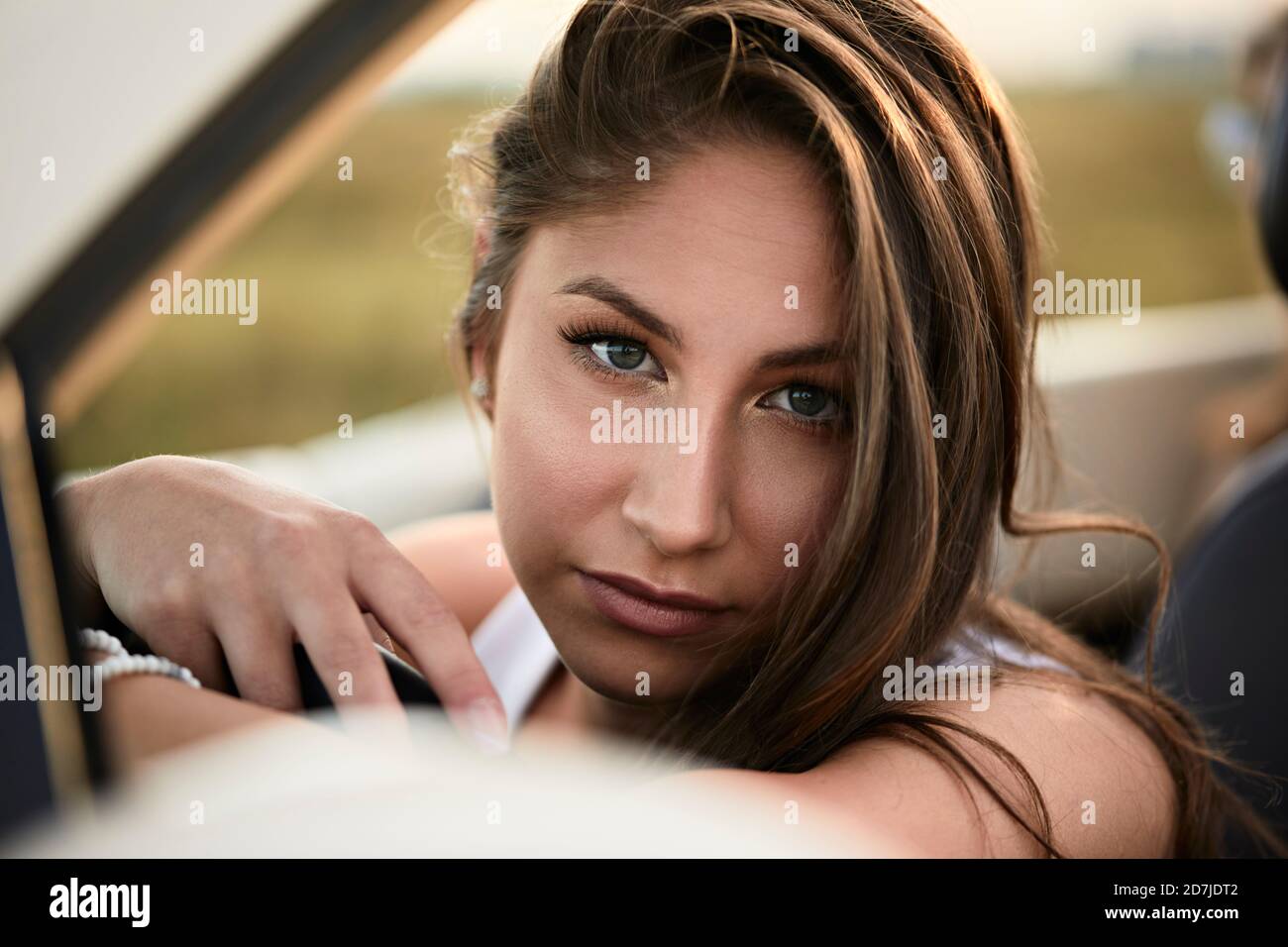 Belle jeune femme assise dans une voiture convertible Banque D'Images