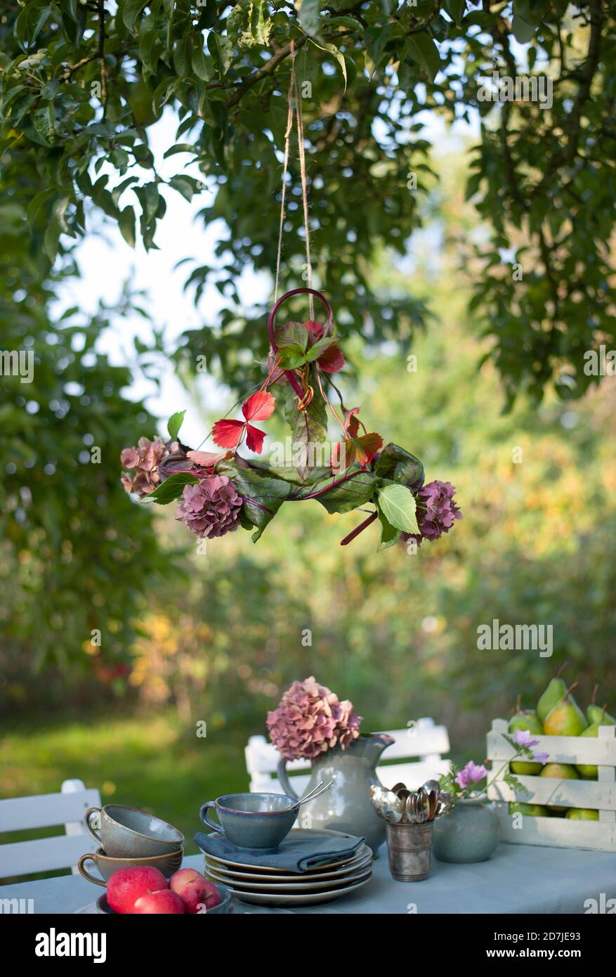 Abat-jour en feuilles et hortensias en fleurs accrochés table basse dans le jardin Banque D'Images