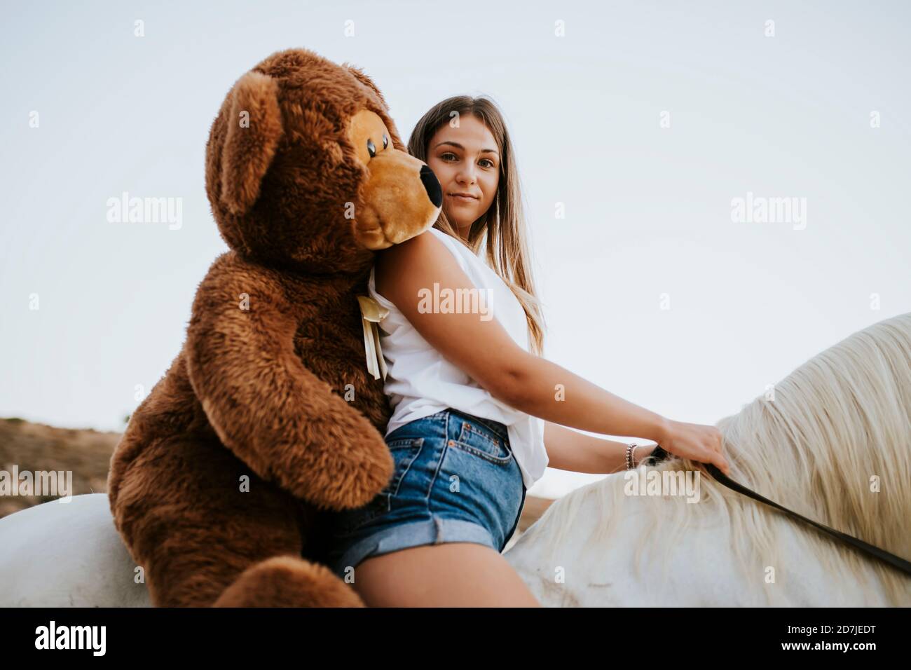 Portrait de la belle jeune femme à cheval avec grand teddy à porter derrière vous Banque D'Images