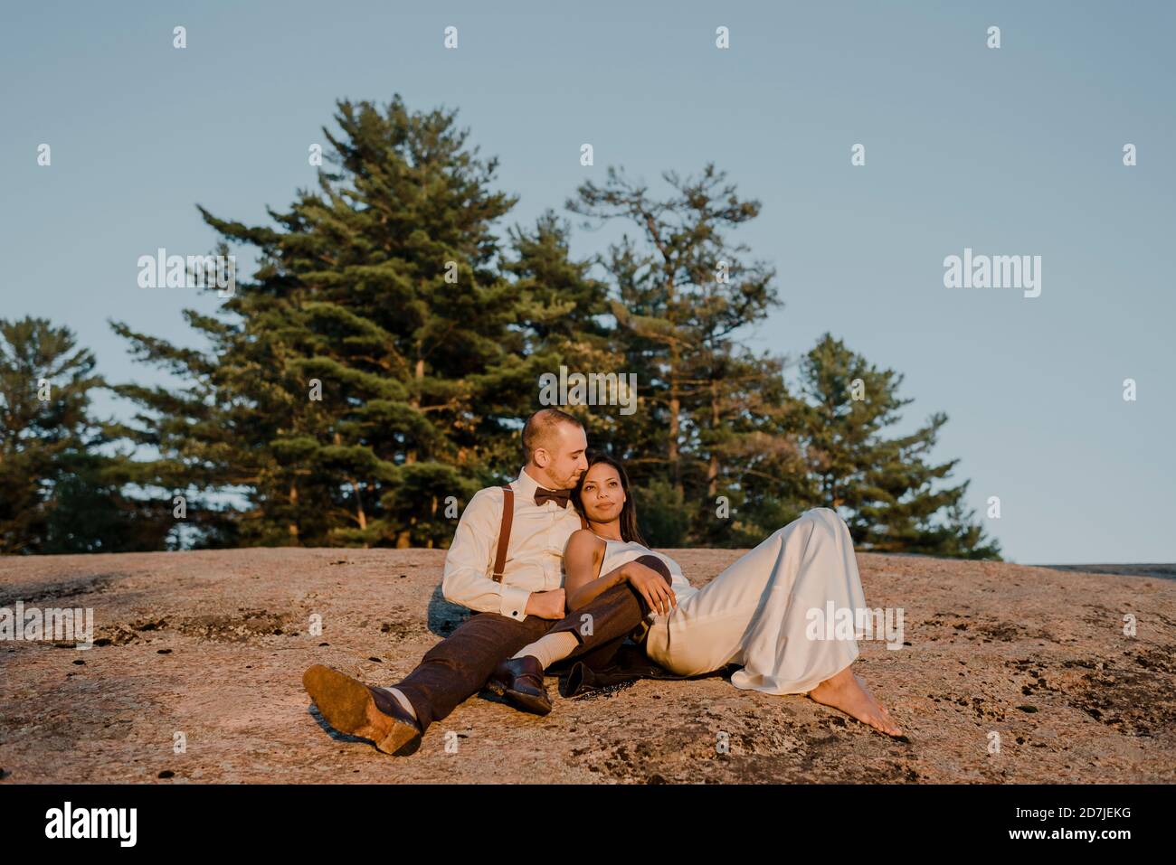 Couple assis dans la forêt pendant le coucher du soleil Banque D'Images