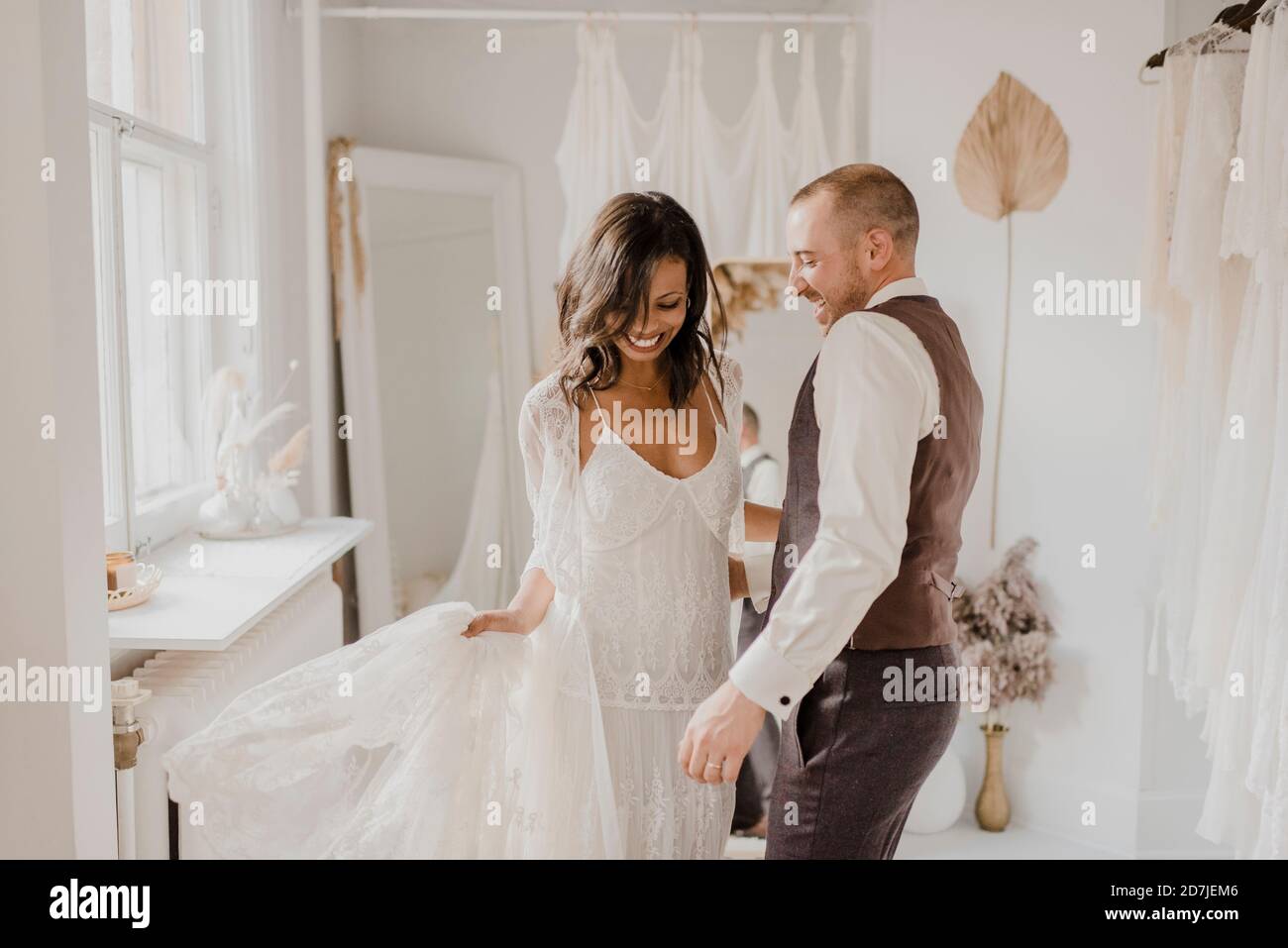 Couple souriant dansant à la boutique de robes de mariée Banque D'Images