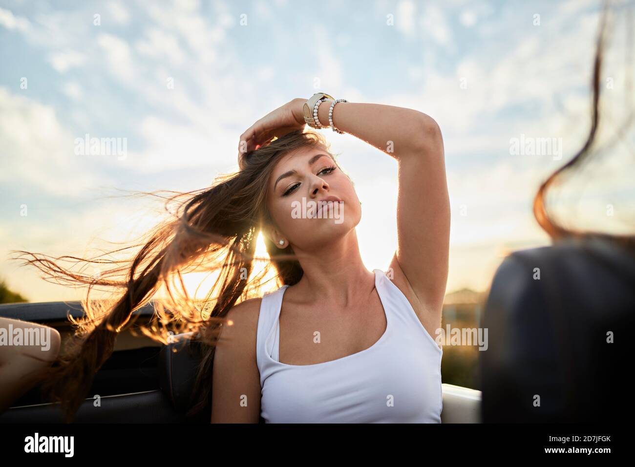 Jeune femme regardant loin en étant assise dans le cabriolet contre le ciel au coucher du soleil Banque D'Images