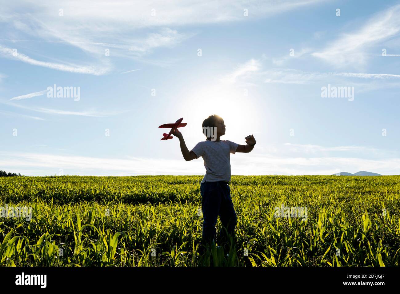 Silhouette de garçon jouant avec un jouet d'avion contre le ciel clair Banque D'Images