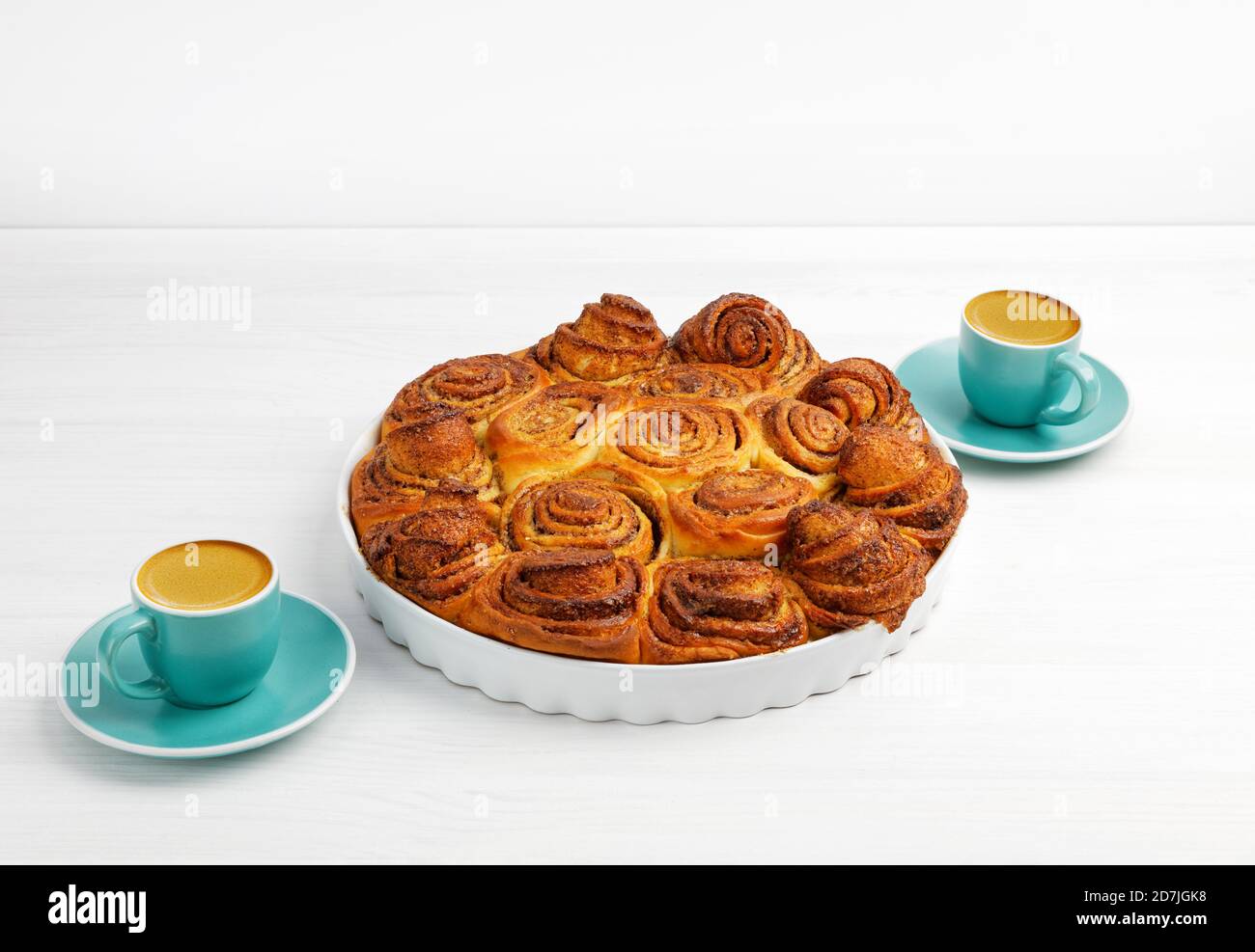 Petits pains à la cannelle faits maison à partir de pâte de levure et deux tasses d'espresso de café sur une table en bois blanc. CopySpace. Banque D'Images Petits pains à la cannelle faits maison à partir de pâte de levure et deux tasses d'espresso de café sur une table en bois blanc. CopySpace. Banque D'Images
