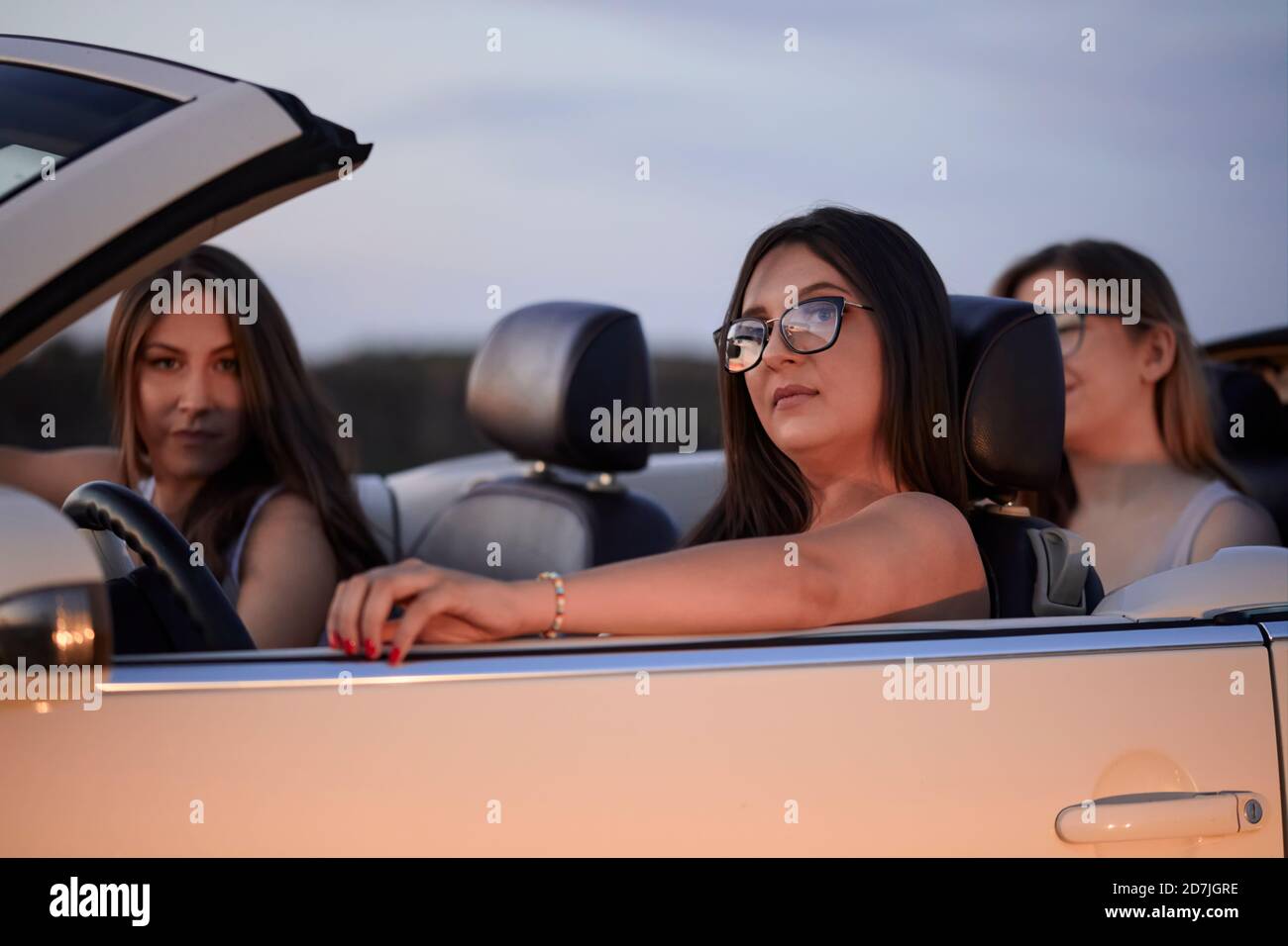 Des amies de sexe féminin assis dans un présentoir convertible contre le ciel à la tombée de la nuit Banque D'Images