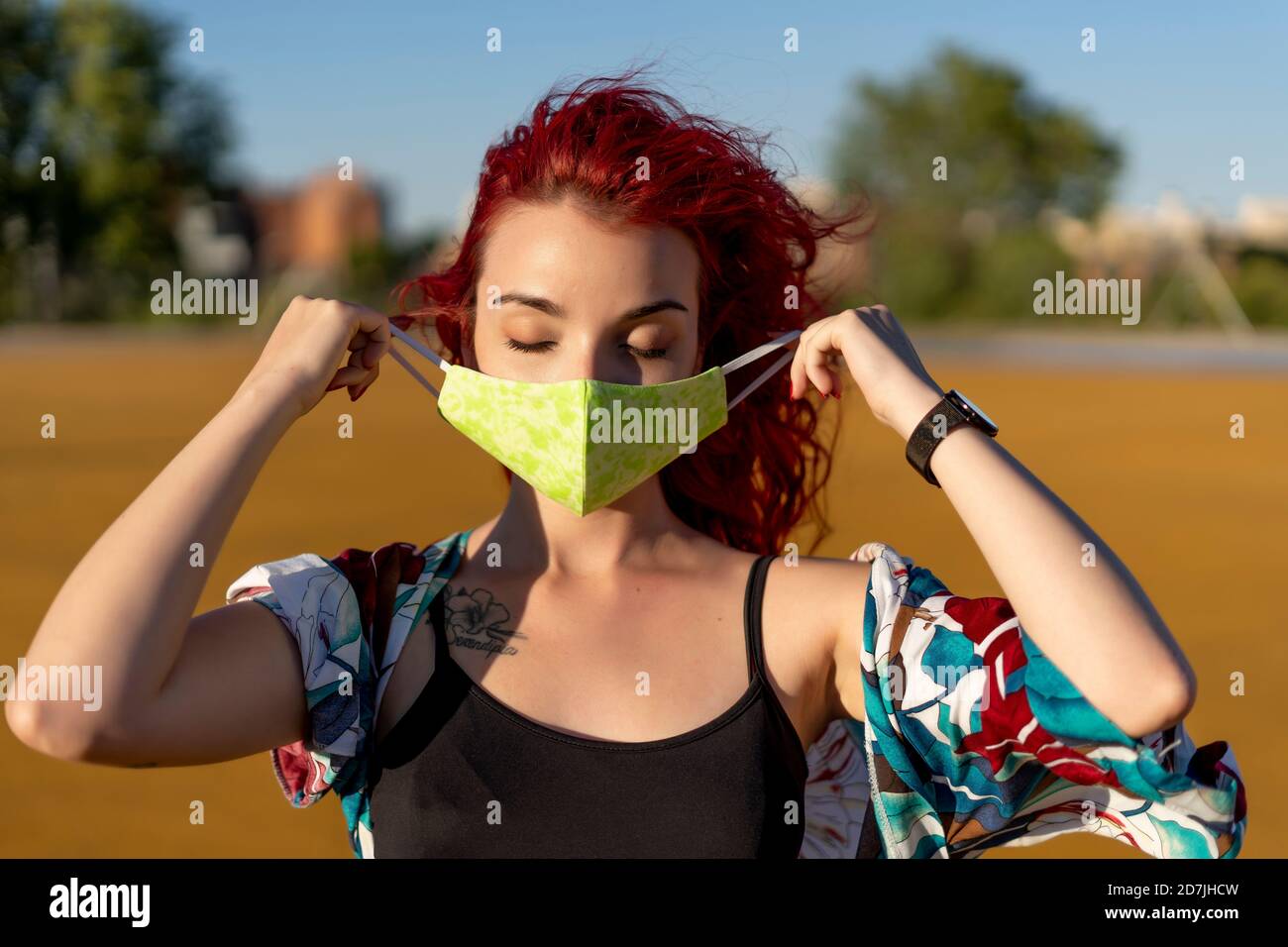 Jeune femme portant un masque de protection tout en se tenant debout à l'extérieur jour ensoleillé Banque D'Images
