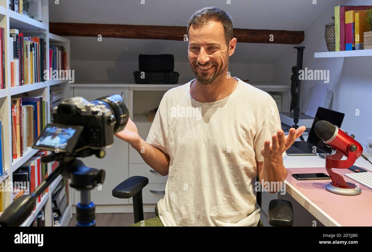 Homme souriant enregistrant un didacticiel vidéo sur l'appareil photo de chez lui Banque D'Images