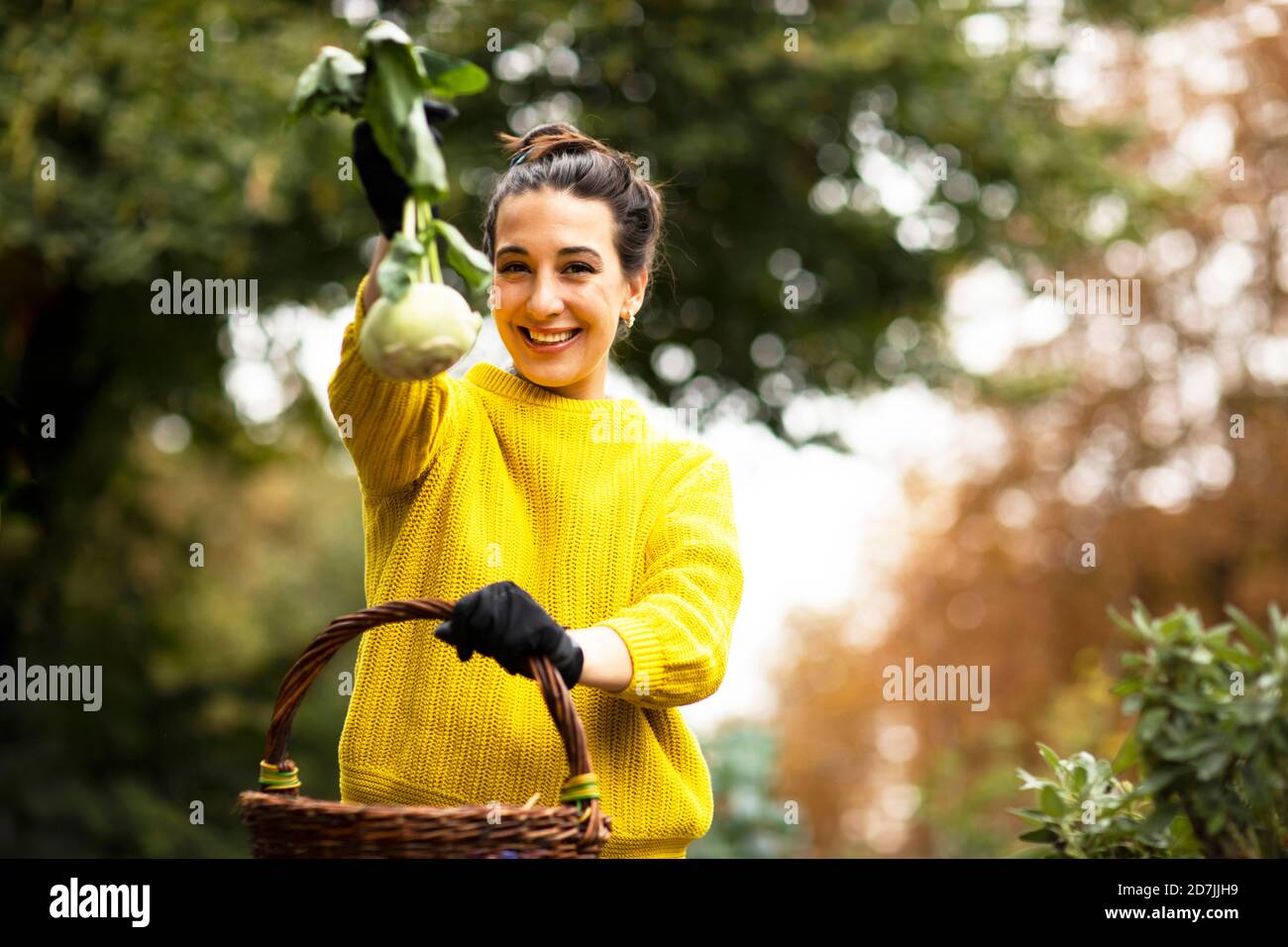 Femme montrant le kohlrabi en se tenant dans un jardin urbain Banque D'Images