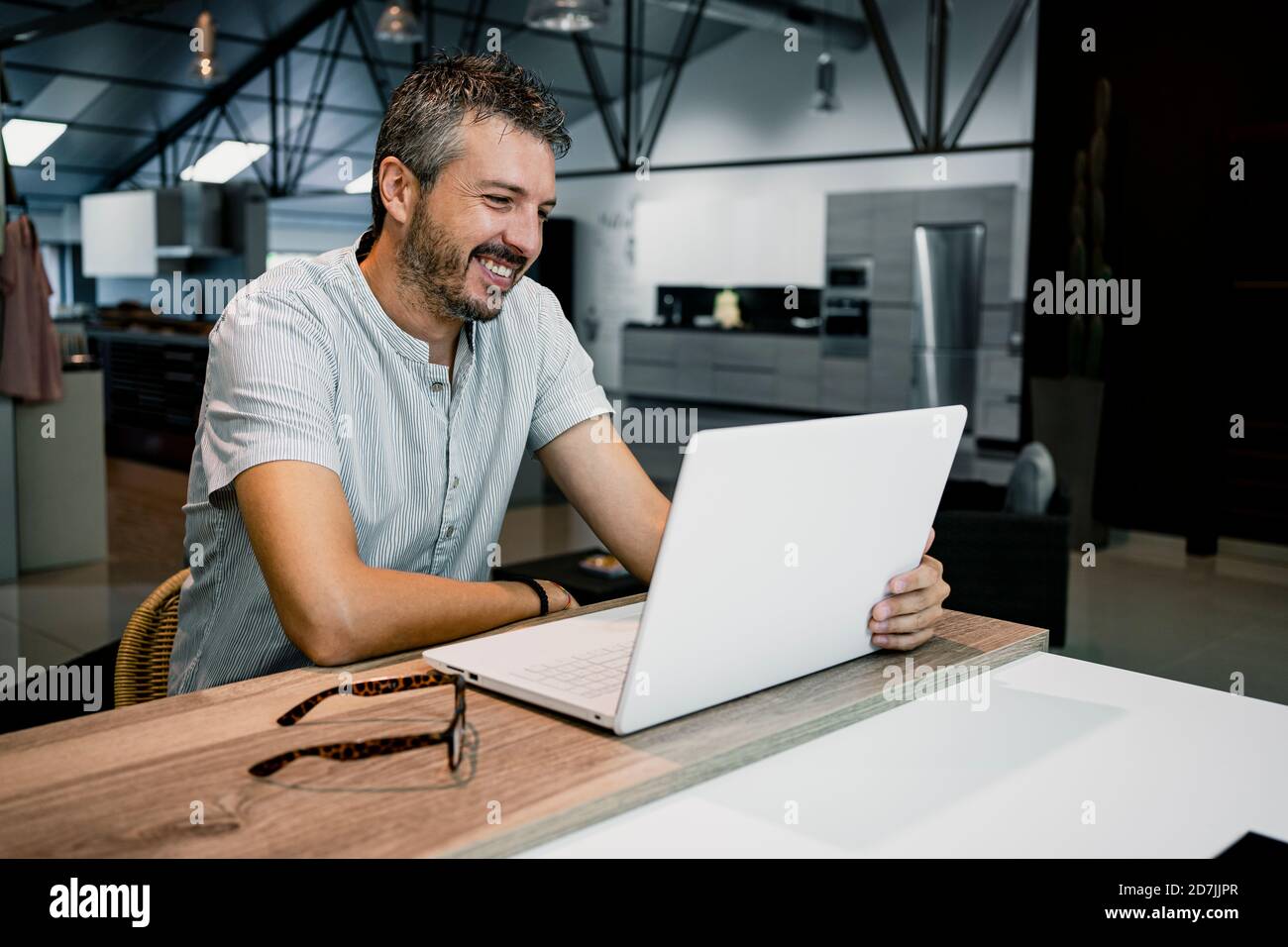 Souriant homme professionnel regardant un ordinateur portable tout en faisant du travail indépendant au bureau Banque D'Images