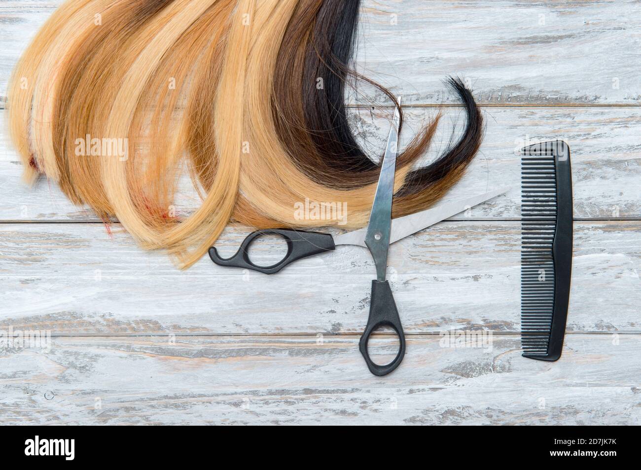 Ciseaux de coiffeur avec peigne et mèche de cheveux sur fond en bois.  Service de coiffure Photo Stock - Alamy