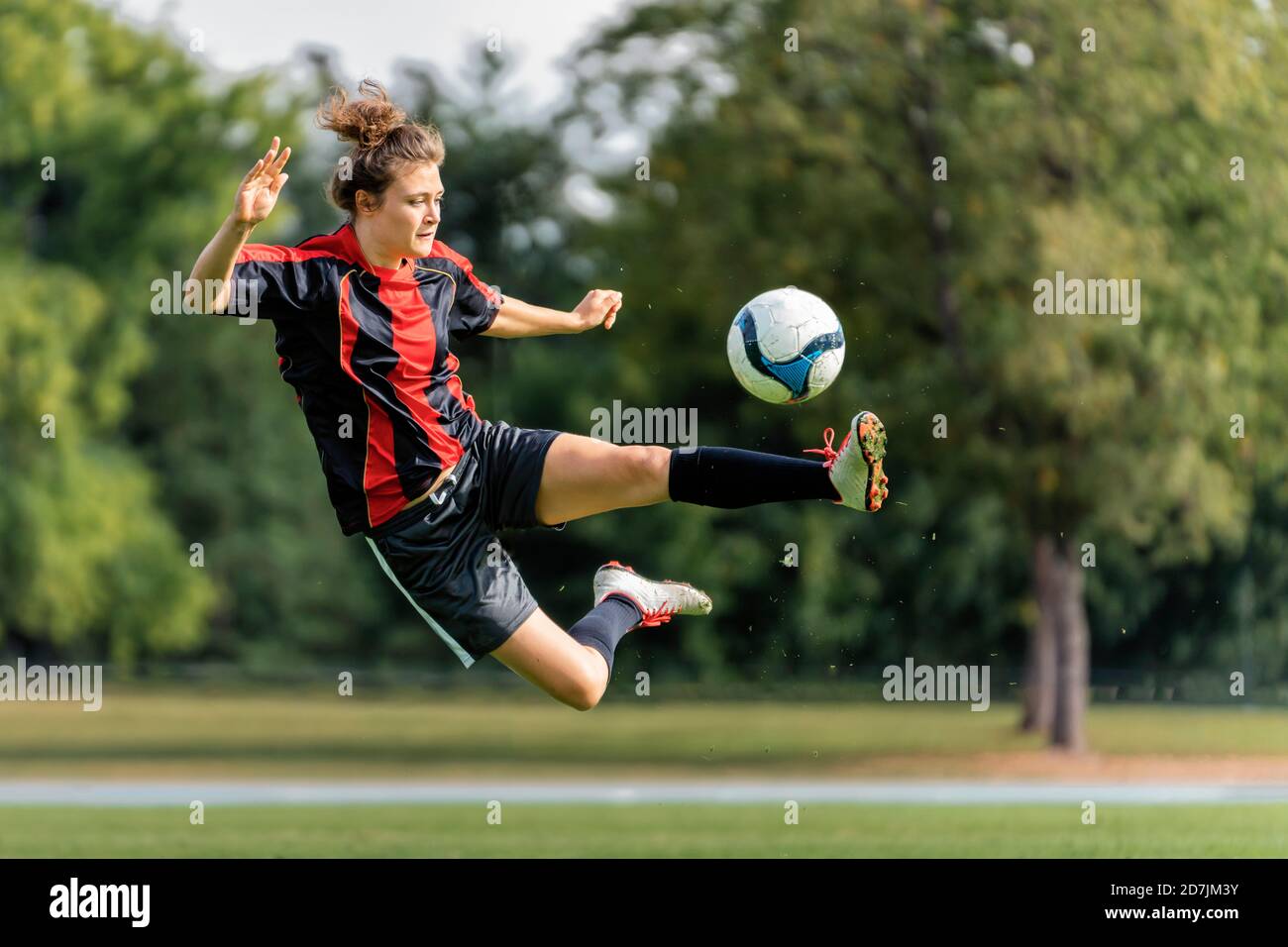 Jeune femme jouant au football sur le terrain Banque D'Images