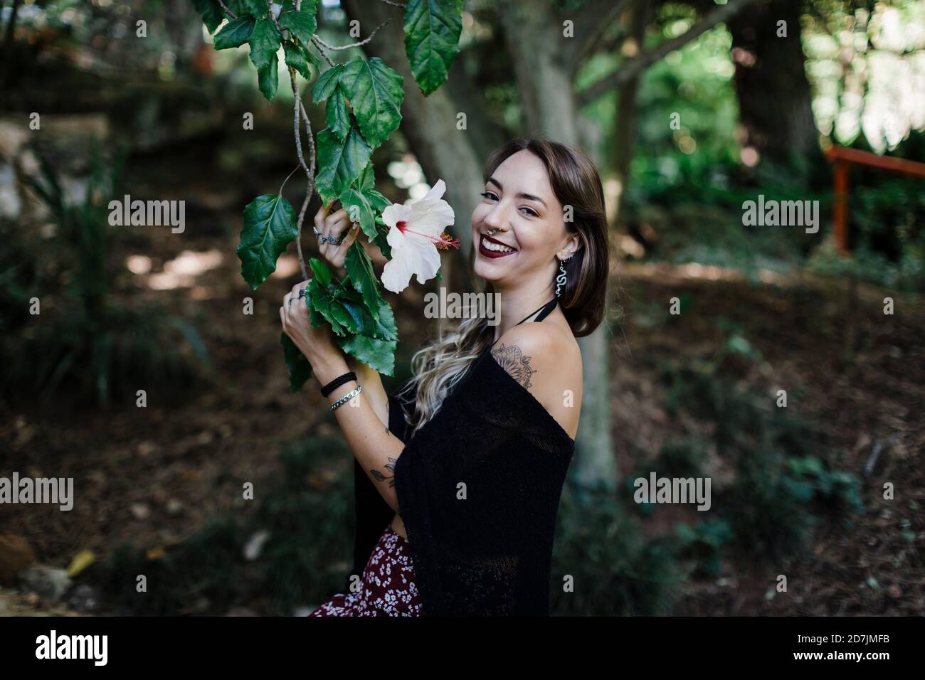 Femme souriante tenant une plante de fleur tout en se tenant au parc Banque D'Images