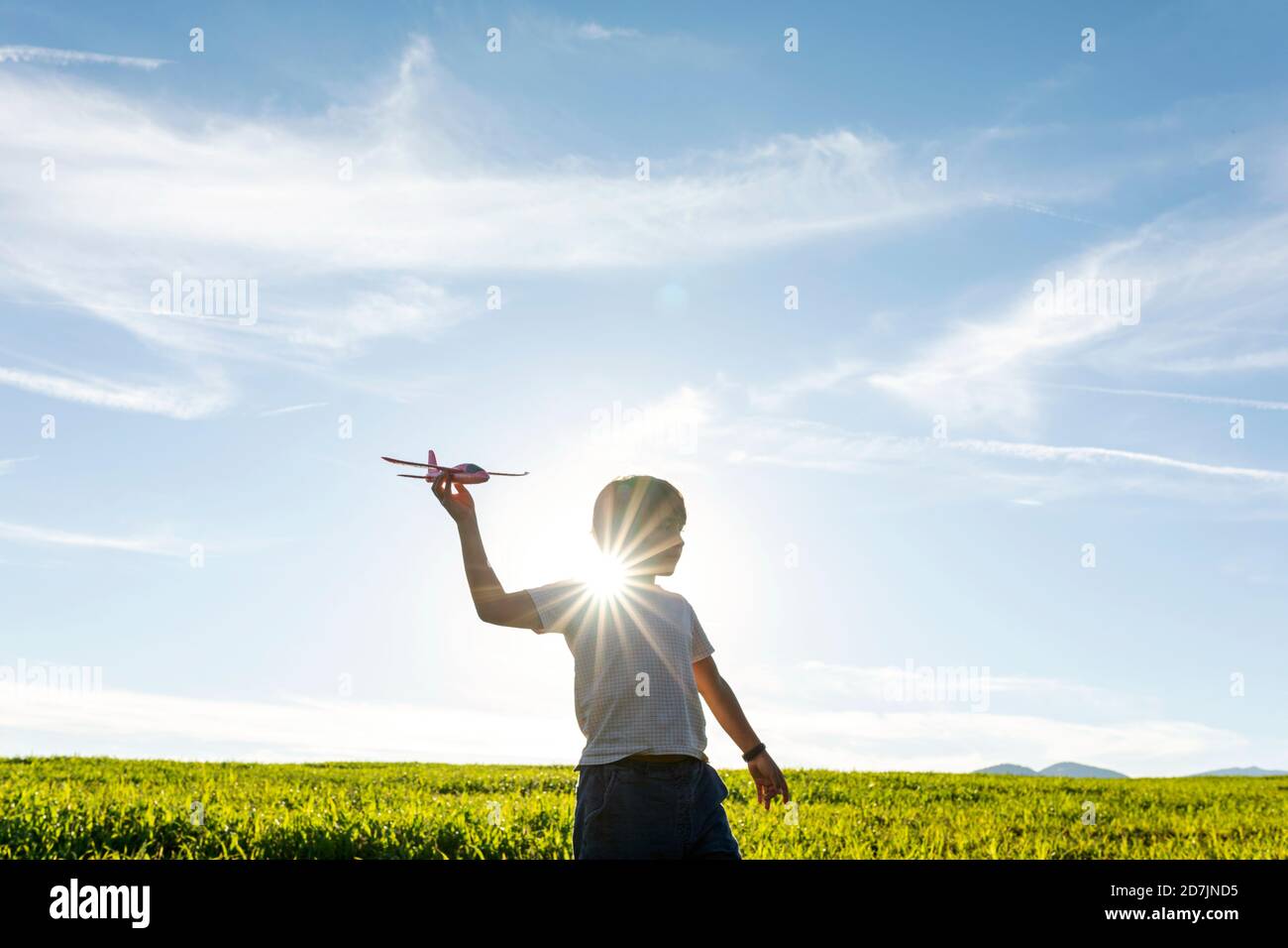Garçon joueur tenant le jouet d'avion tout en se tenant contre le ciel clair Banque D'Images