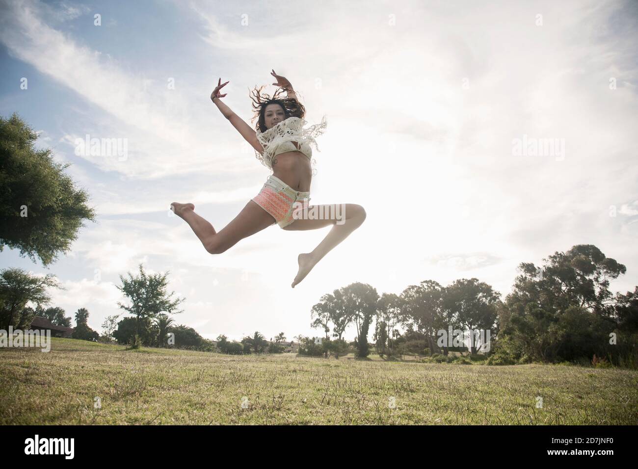 Une jeune femme sautant dans un parc public contre un ciel dégagé Banque D'Images