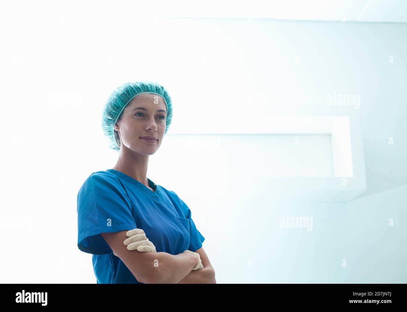 Femme chirurgien confiante debout avec les bras croisés en soins intensifs unité à l'hôpital Banque D'Images Femme chirurgien confiante debout avec les bras croisés en soins intensifs unité à l'hôpital Banque D'Images