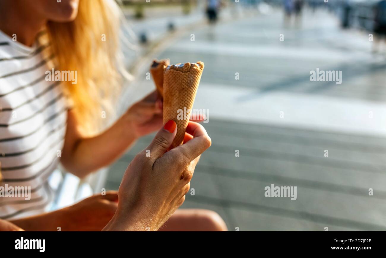 Les jeunes femmes mangent de la glace tout en passant du temps libre à l'intérieur ville par beau temps Banque D'Images