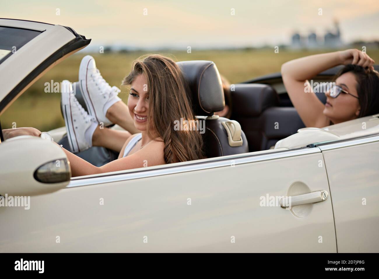 Amis voyageant pour un voyage en voiture de luxe pendant le coucher du soleil Banque D'Images