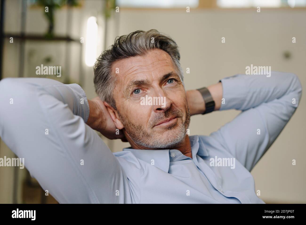 Homme d'affaires avec les mains derrière la tête se détendant au bureau Banque D'Images