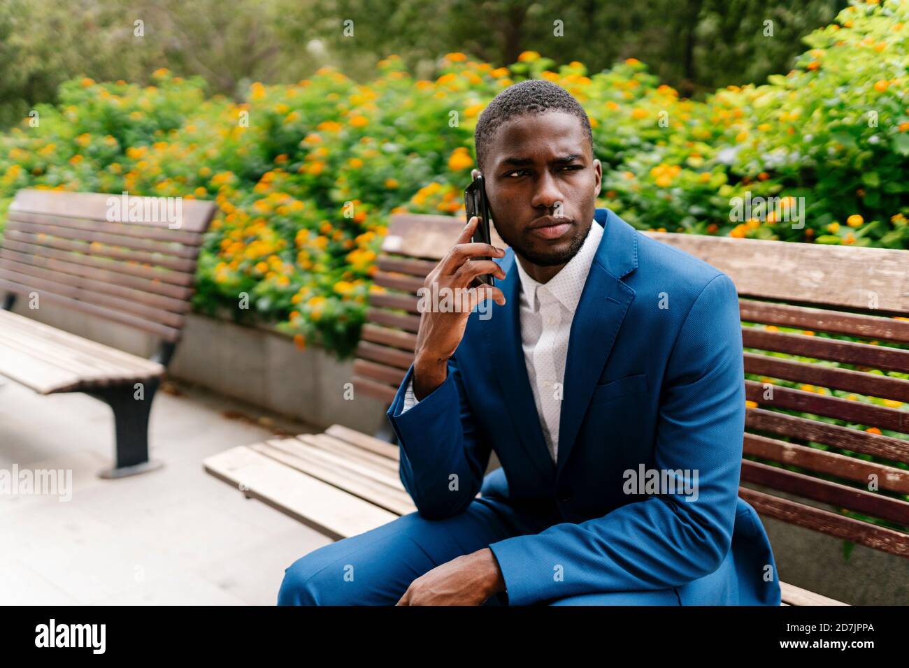 Jeune homme entrepreneur parlant sur téléphone portable tout en regardant loin en ville Banque D'Images
