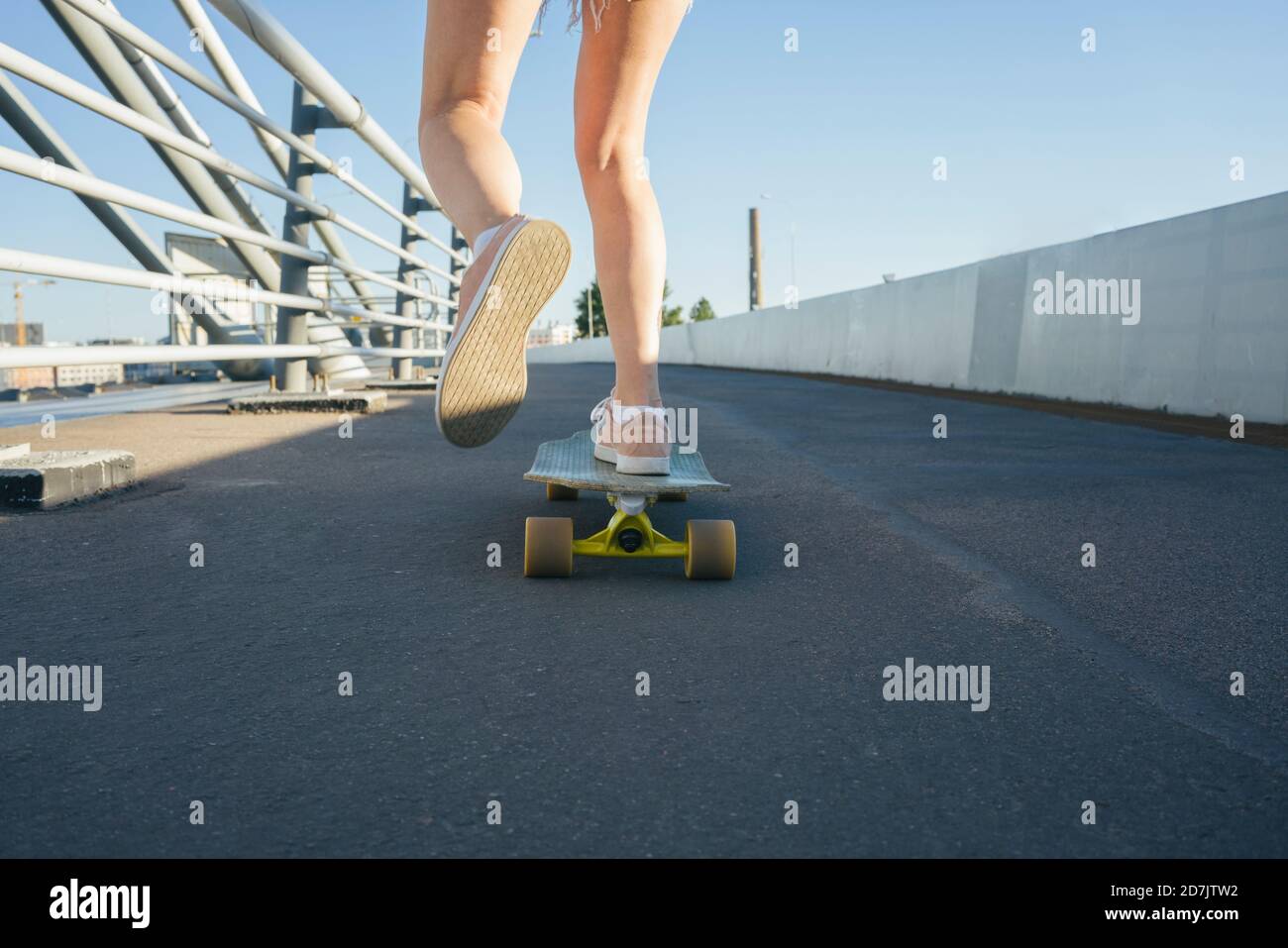 Jambes de femme patinant sur le pont pendant la journée ensoleillée Banque D'Images