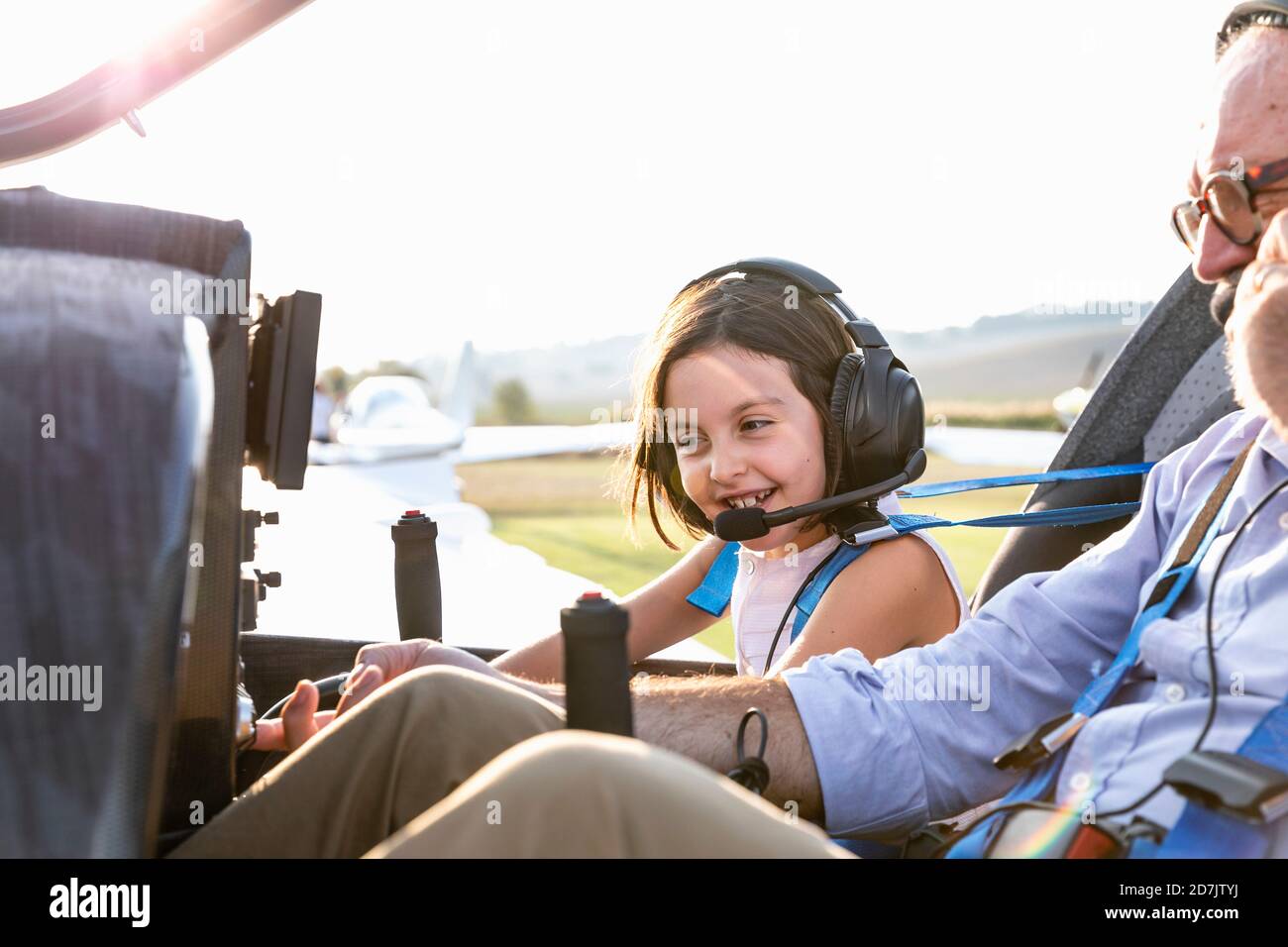 Jeune fille à l'intérieur du cockpit de l'avion avec grand-père à l'aérodrome par beau temps Banque D'Images